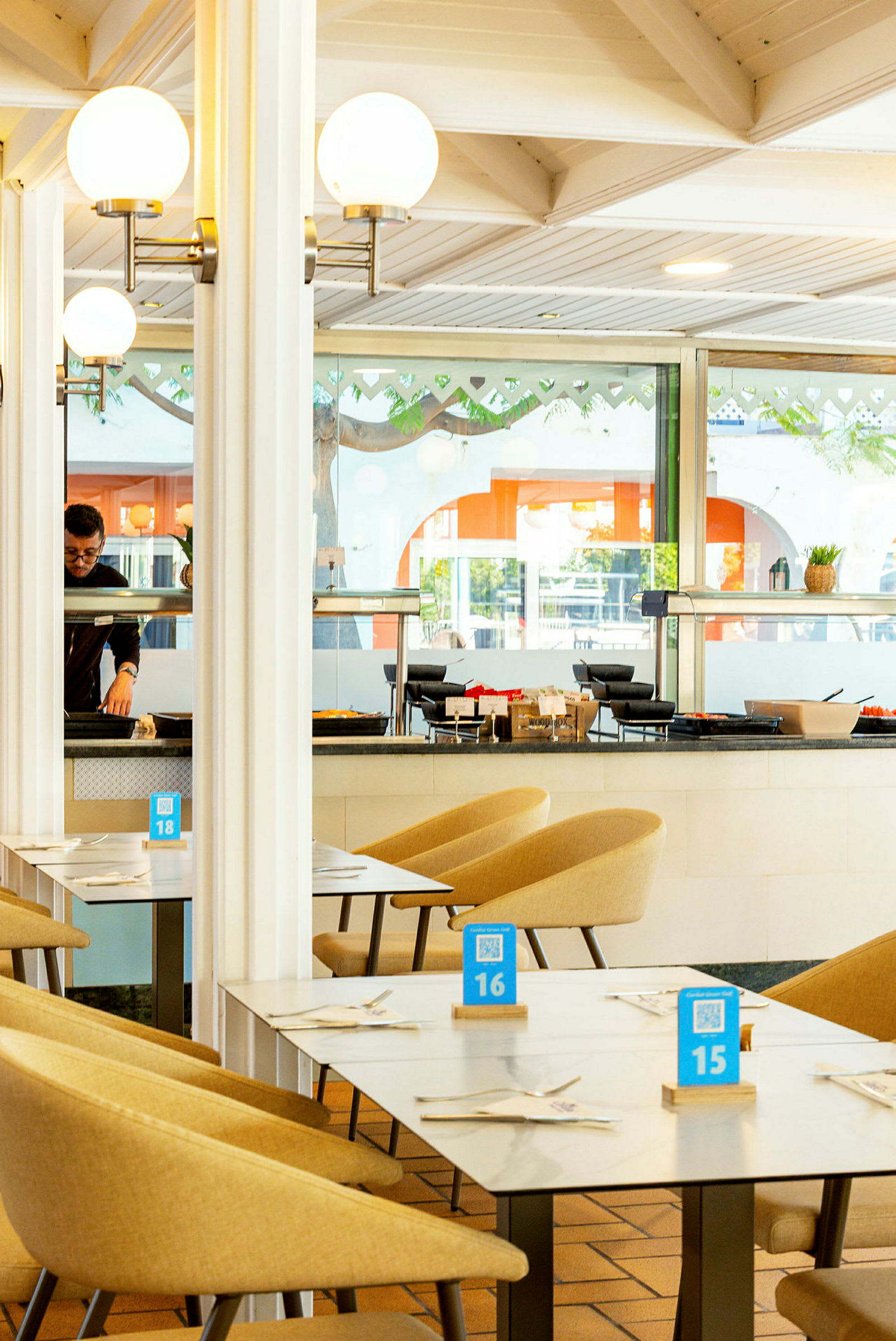 Interiør av en restaurant med bord og stoler, dekorert med lyse farger. (AI-generert tekst)