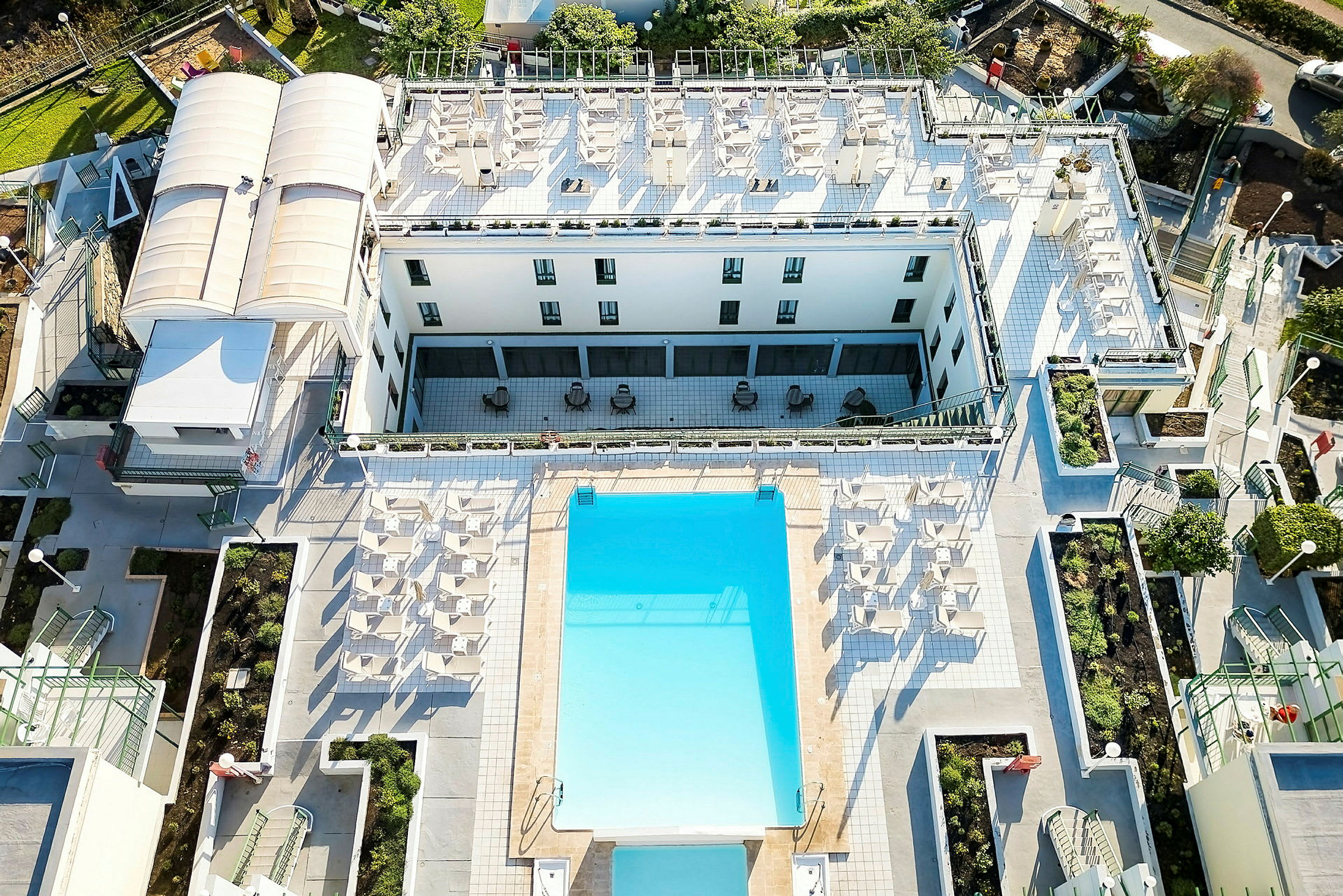 Fugleperspektiv av hotellområde med basseng og solsenger. (AI-generert tekst)