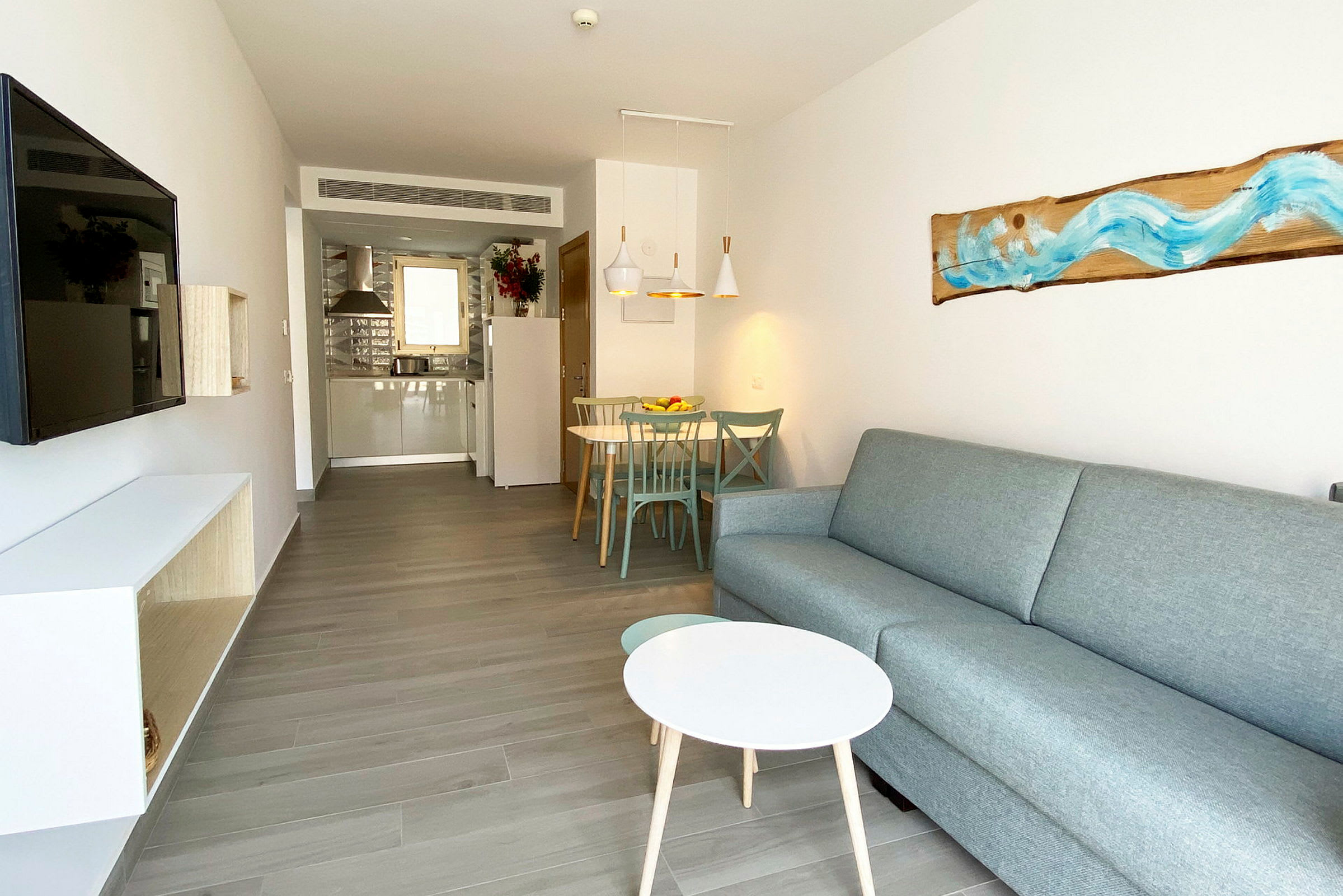 Bilde av et moderne hotellrom med sofa, sofabord, TV og spiseplass. (AI-generert tekst)