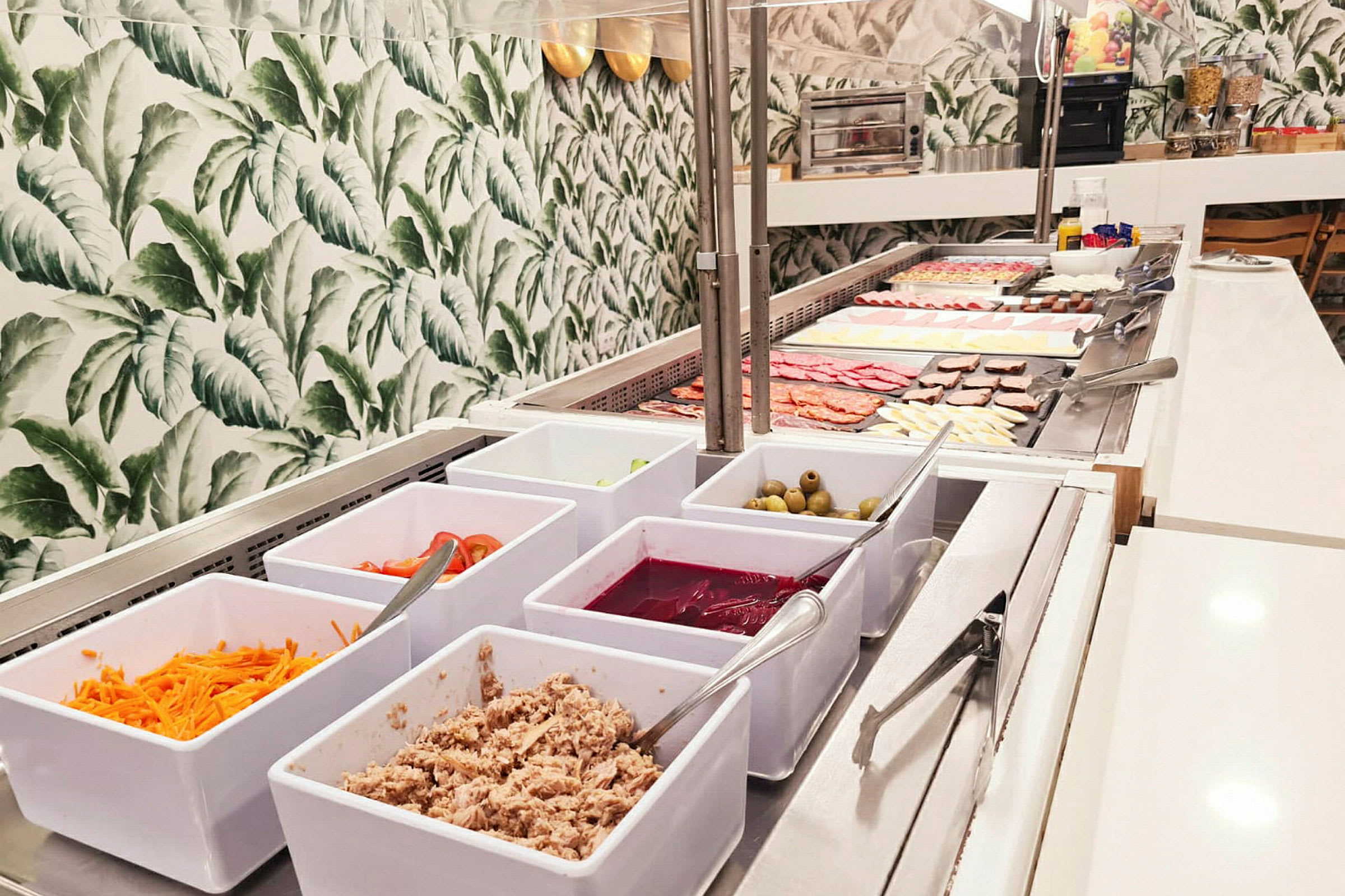 Et bilde av en frokostbuffet med forskjellige tilbehør og matvarer lagt fram i hvite skåler og på serveringsfat. (AI-generert tekst)