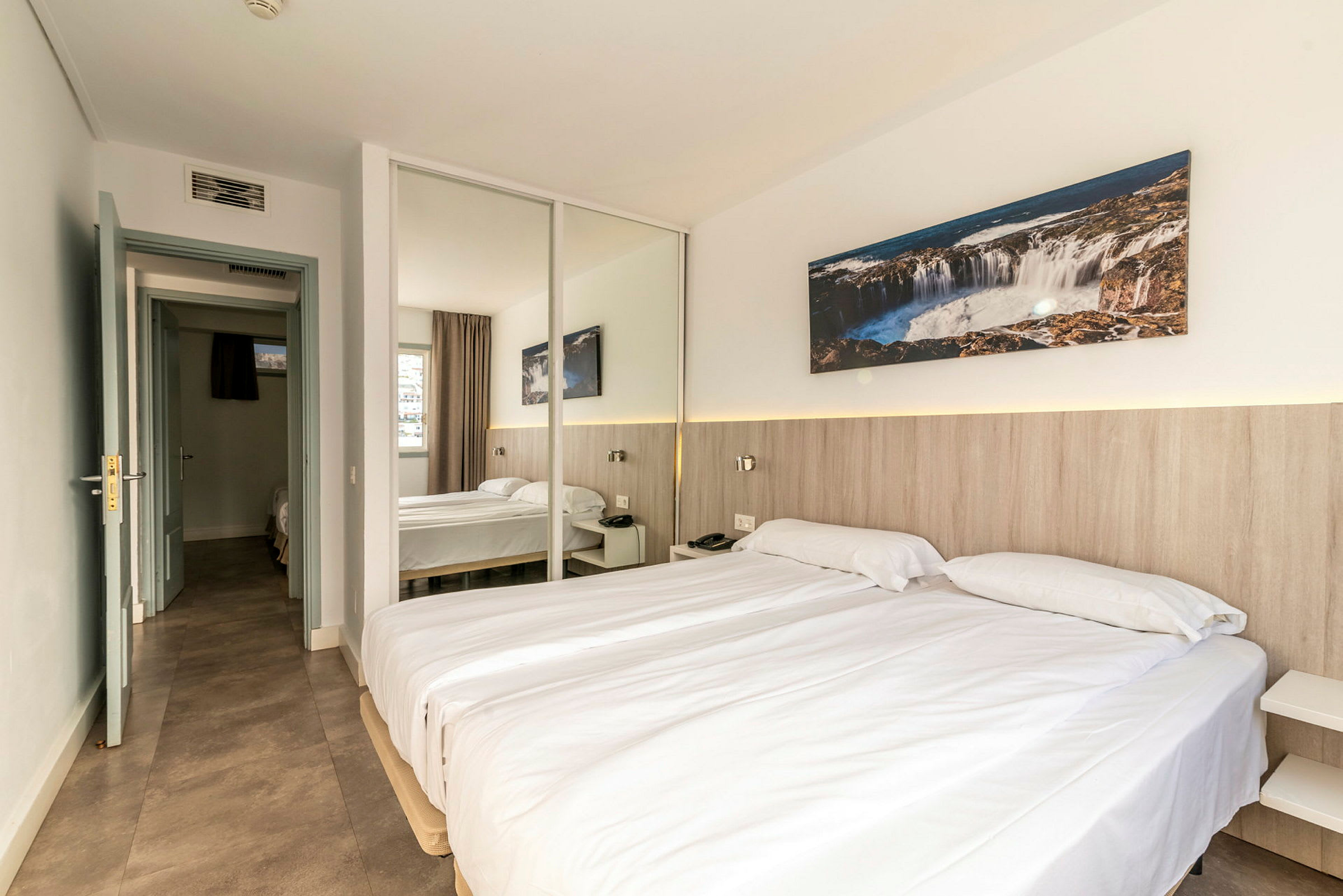 Et hotellrom med to enkeltsenger, en speilvegg og dekorasjoner. (AI-generert tekst)