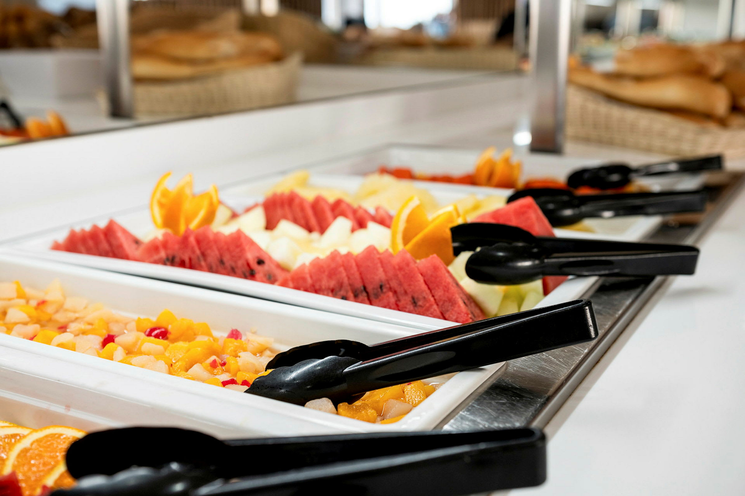 Buffetbord med fersk frukt og salat, inkludert meloner, appelsinskiver og tang. (AI-generert tekst)