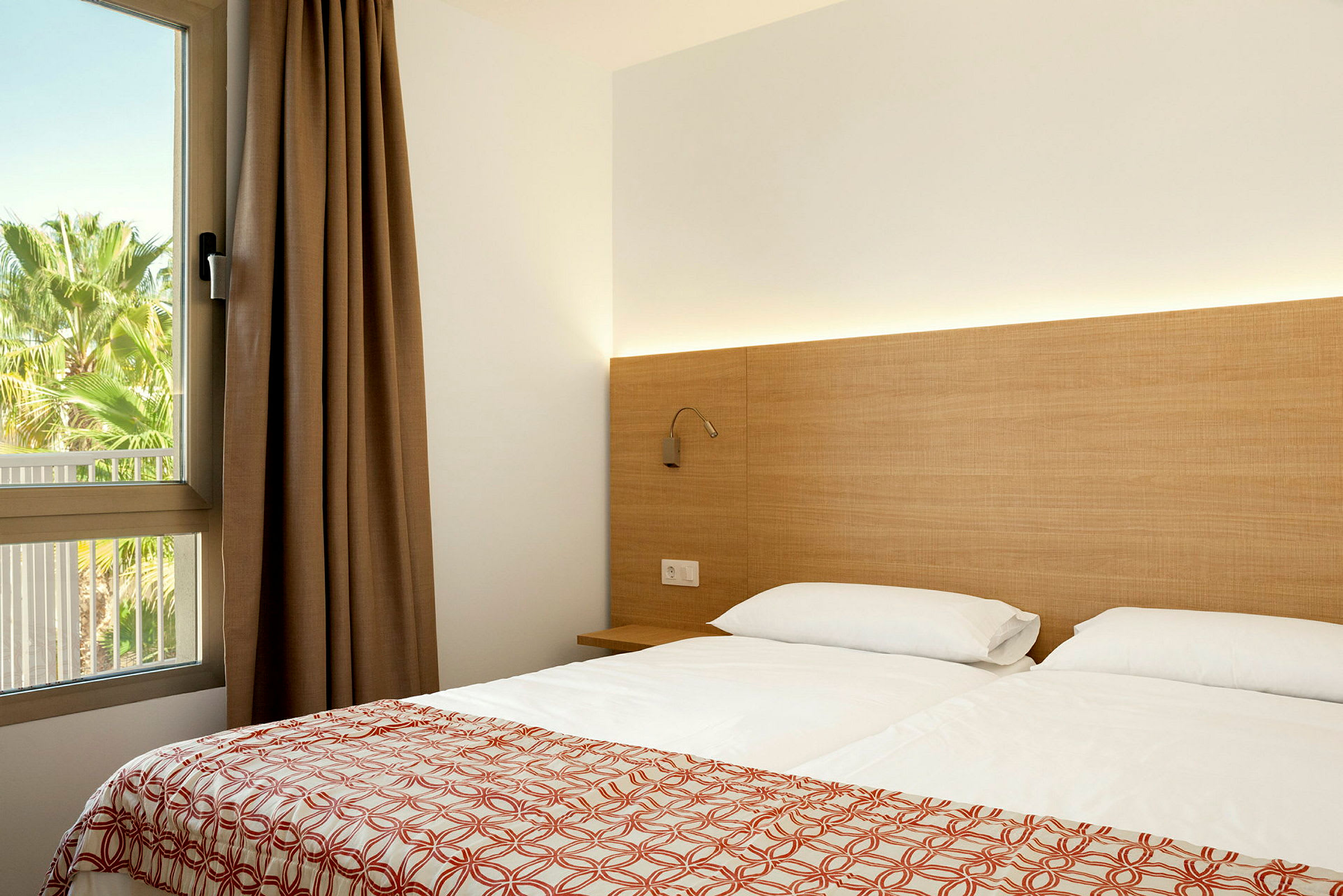 Moderne hotellrom med en dobbeltseng, et nattbord og et vindu med utsikt mot grøntområder. (AI-generert tekst)