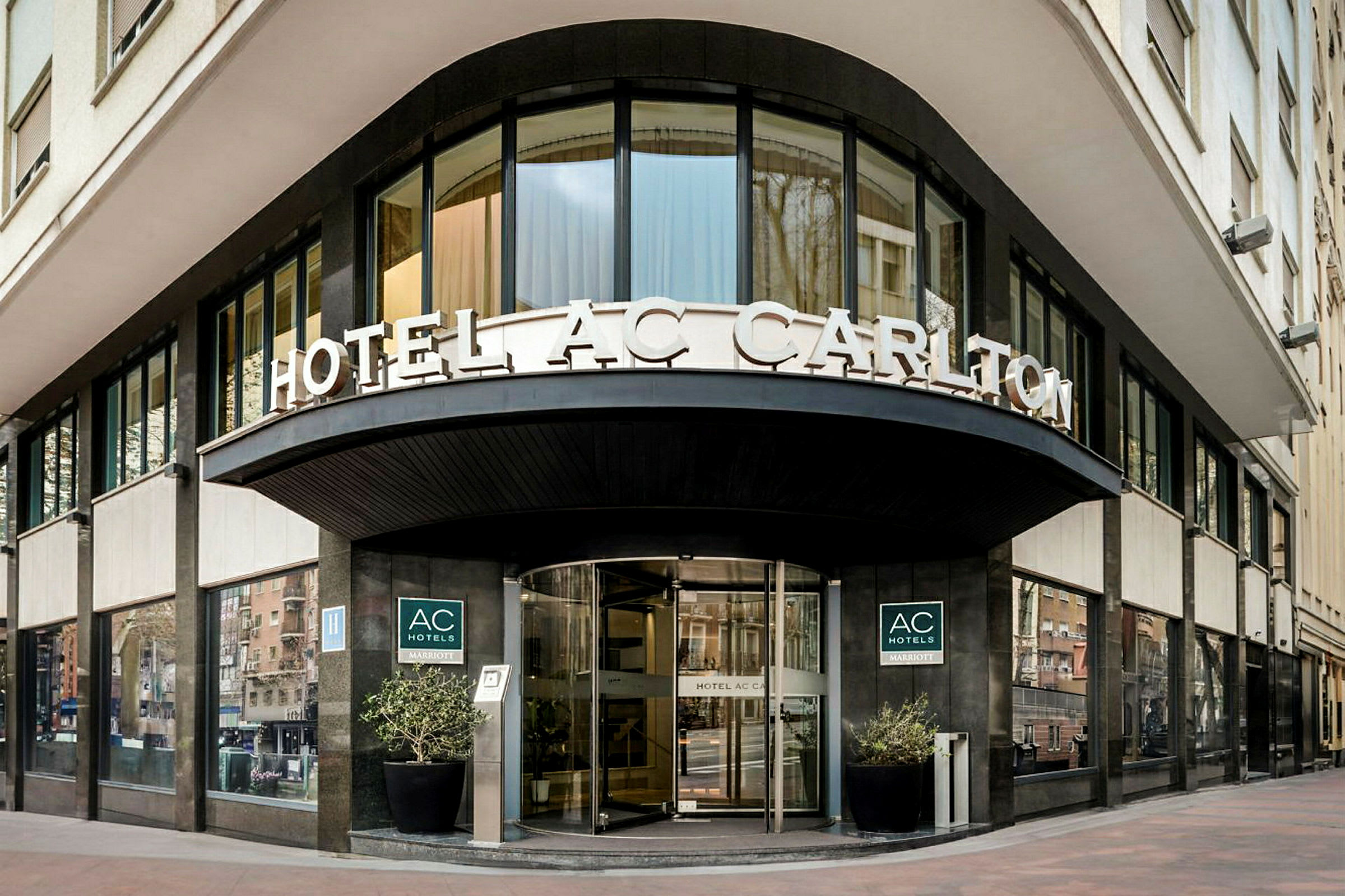 En hotellfasade med skilteteksten "HOTEL AC CARLTON" synlig over inngangen. (AI-generert tekst)