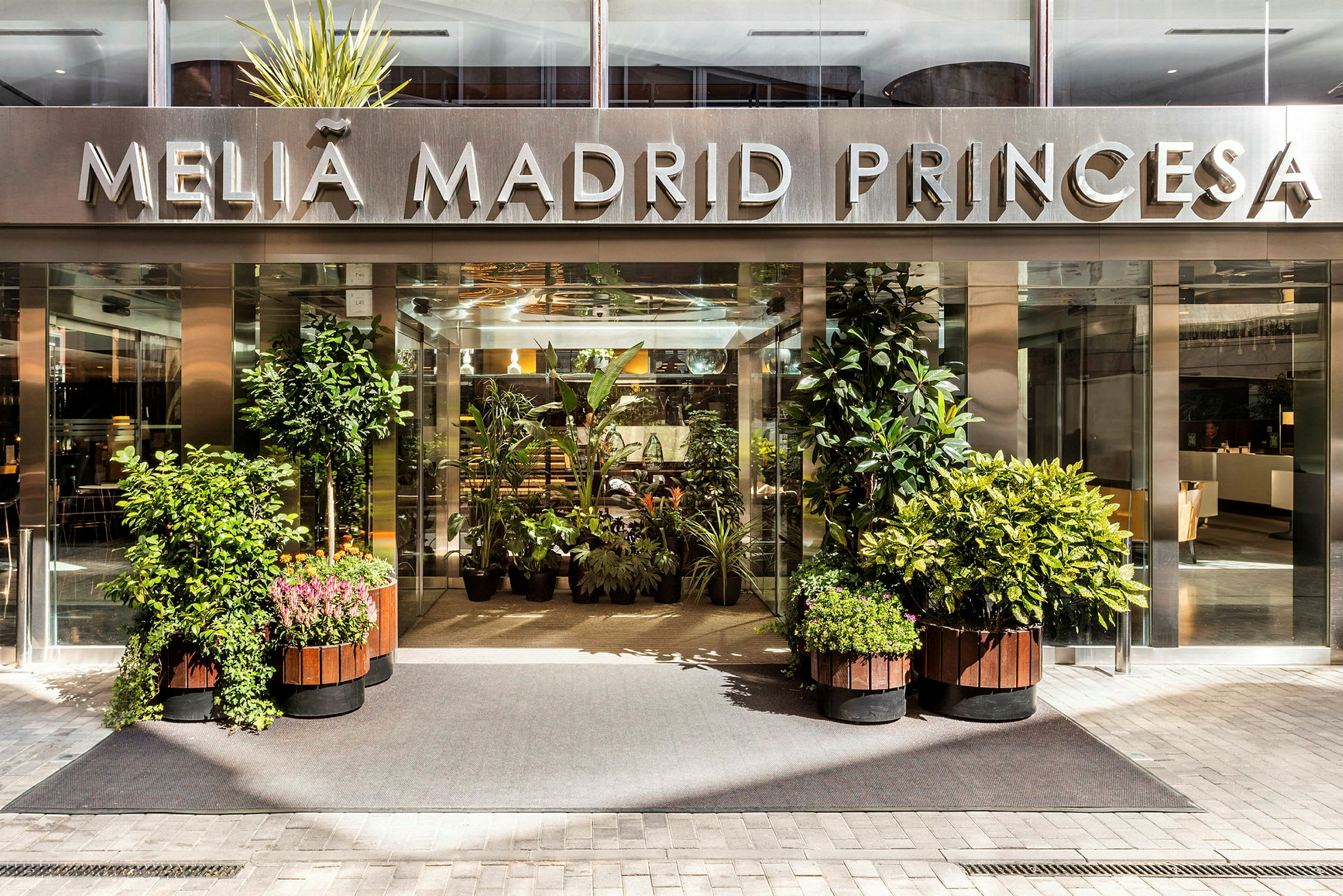 Hotellinngang med skilt "Meliá Madrid Princesa" og omkringliggende planter. (AI-generert tekst)