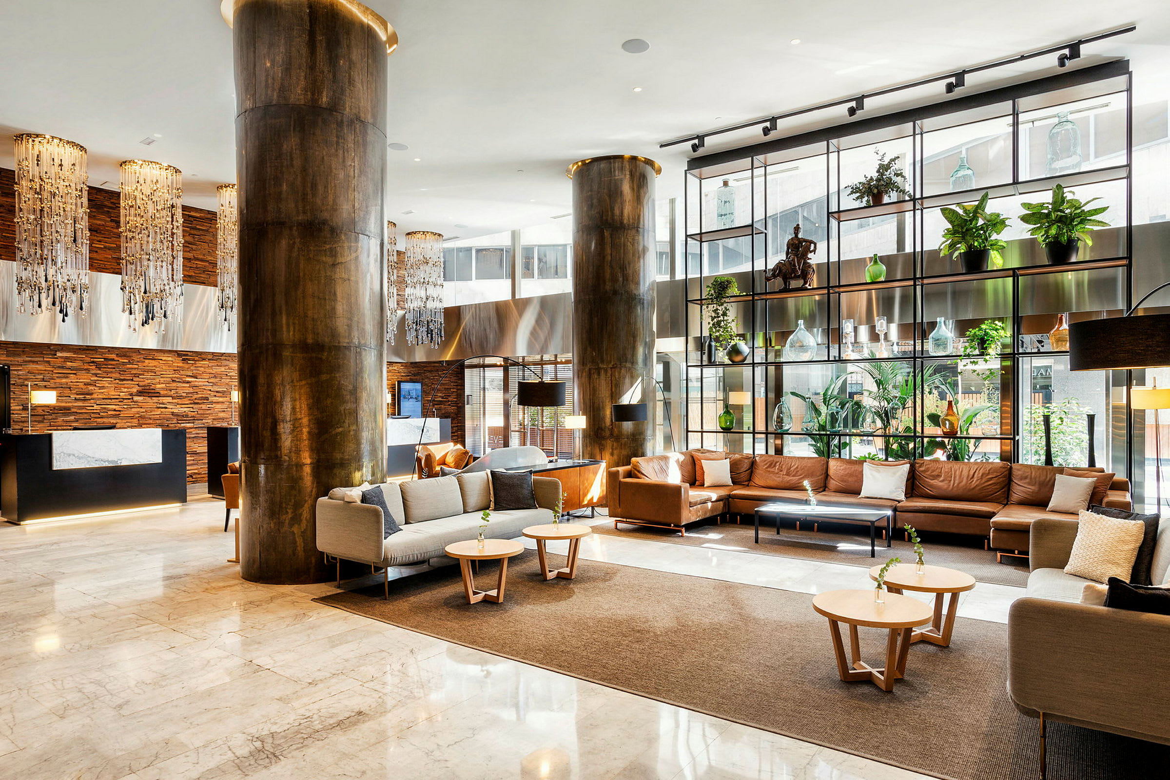 En moderne hotellobby med luksuriøst interiør som inkluderer sofaer og lenestoler, dekorasjoner, planter og belysning. (AI-generert tekst)