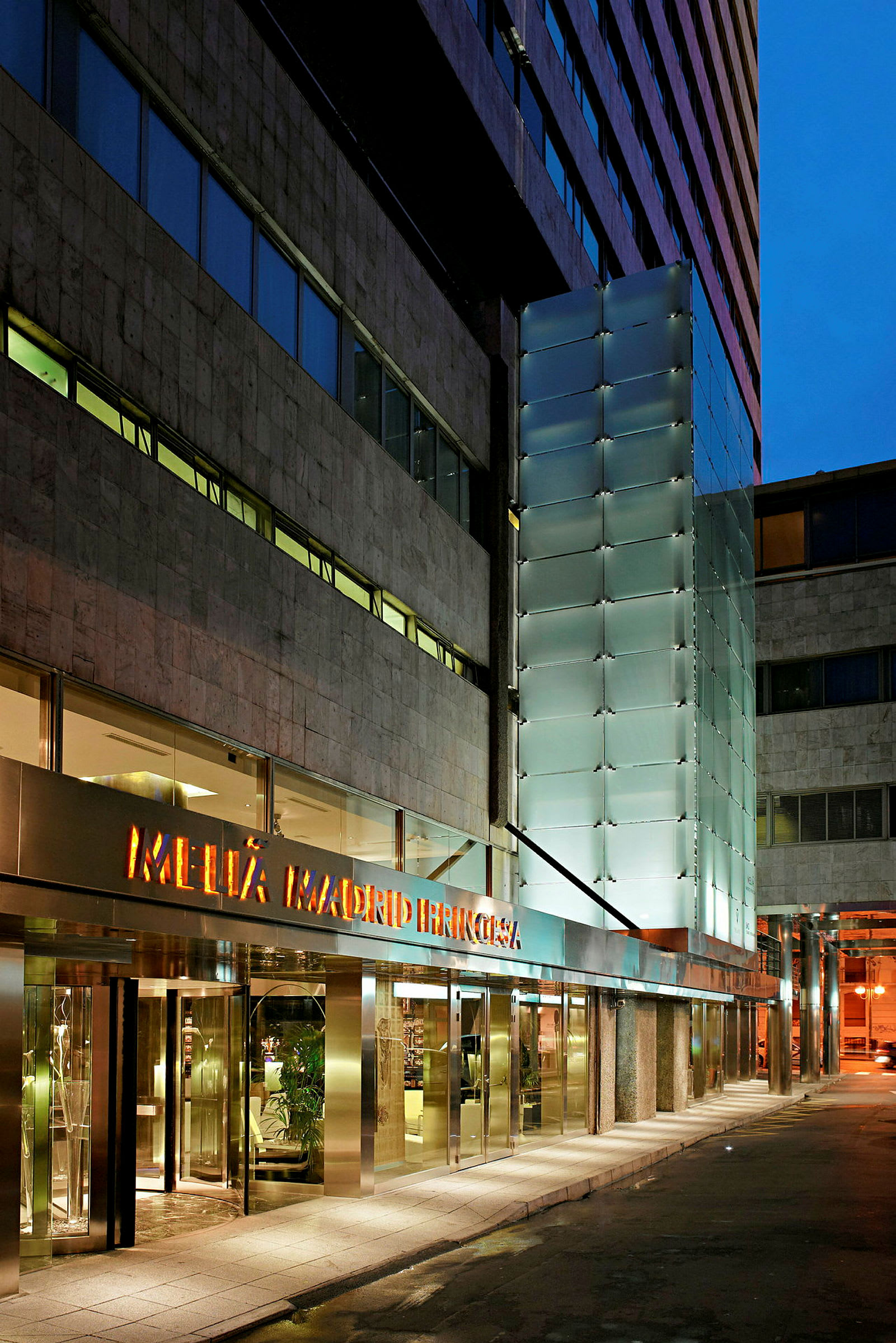 Inngangen til et hotell med glass- og marmorfasade. (AI-generert tekst)