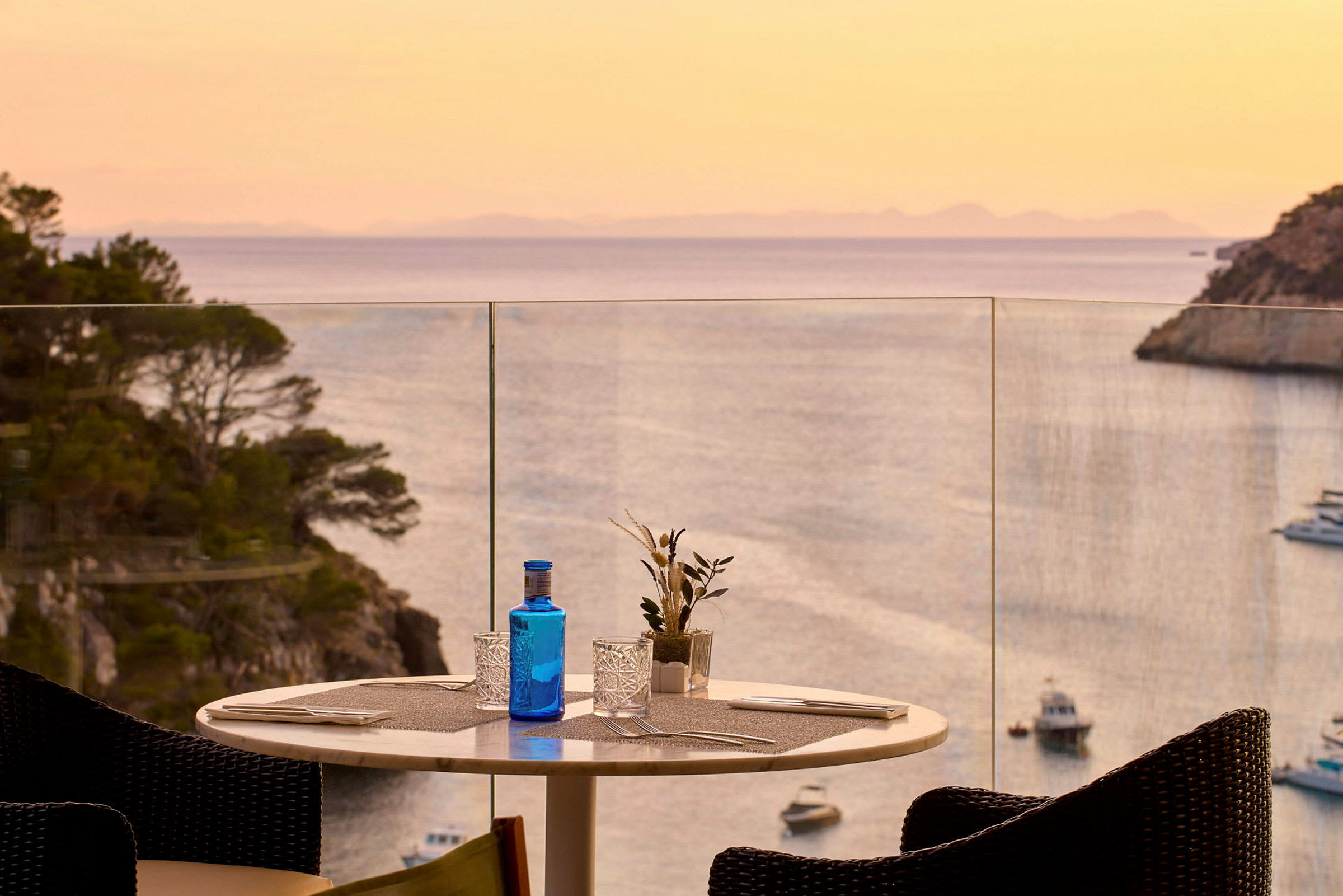 Et dekket bord på en terrasse med utsikt over havet og en solnedgang. (AI-generert tekst)