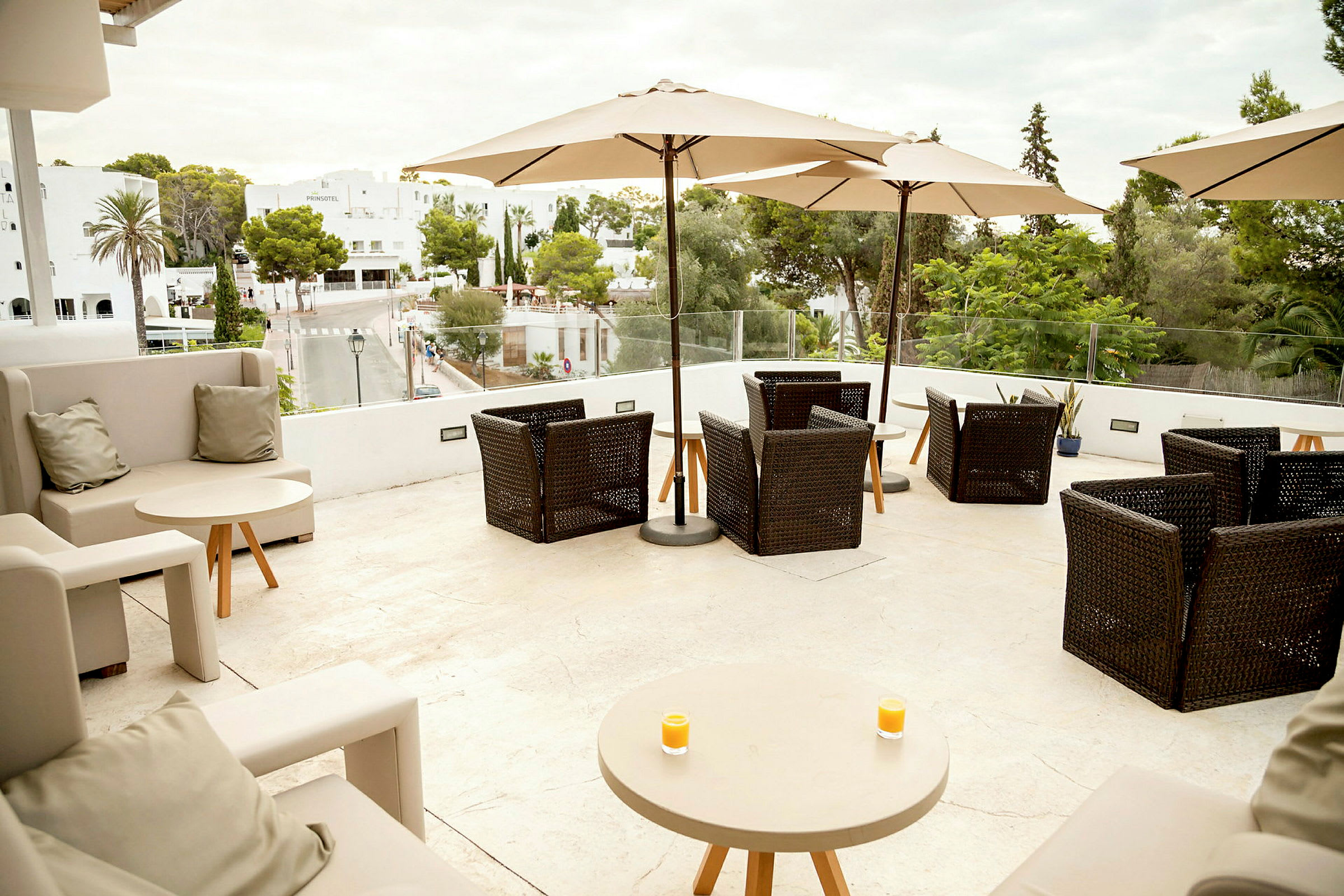 Terrasse med sitteplasser og parasoller, utsikt mot grøntområder og bygninger. (AI-generert tekst)