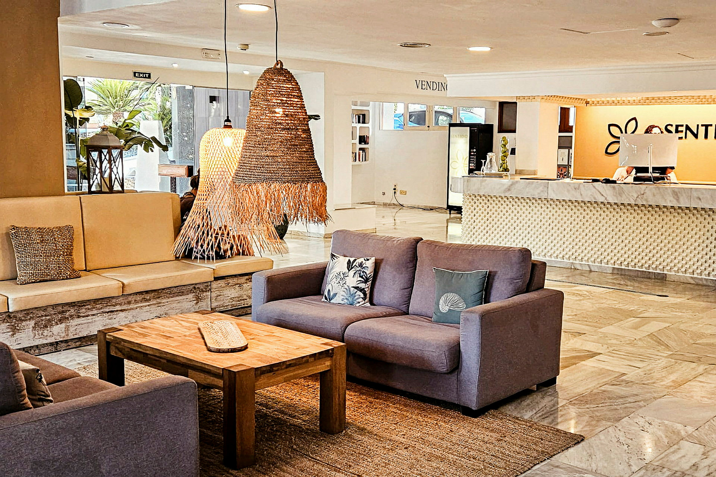 En hotellobby med sittegrupper, bord og resepsjon. (AI-generert tekst)