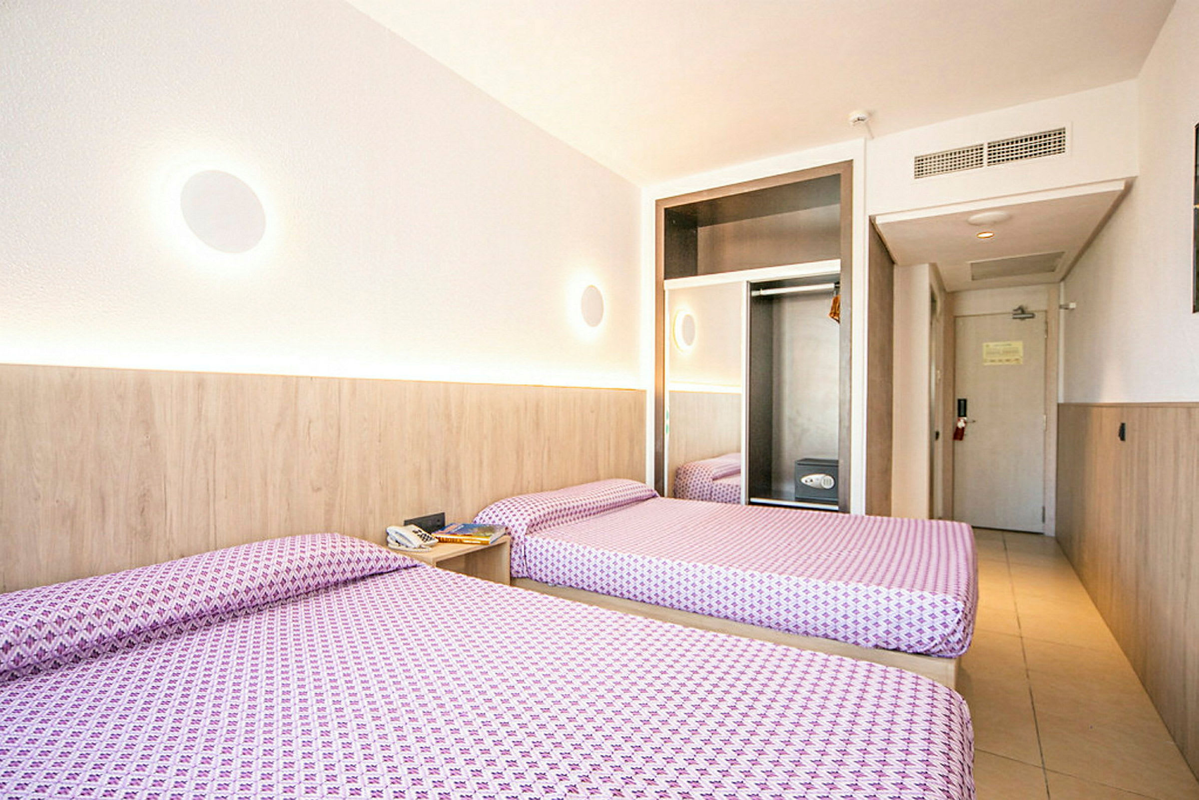 Hotellrom med to enkeltsenger, garderobe og dør. (AI-generert tekst)