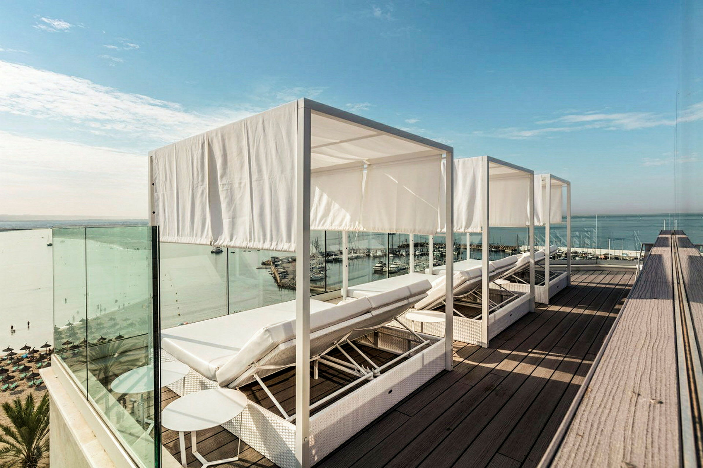 Solstoler med hvite gardiner på en terrasse med utsikt over havet. (AI-generert tekst)