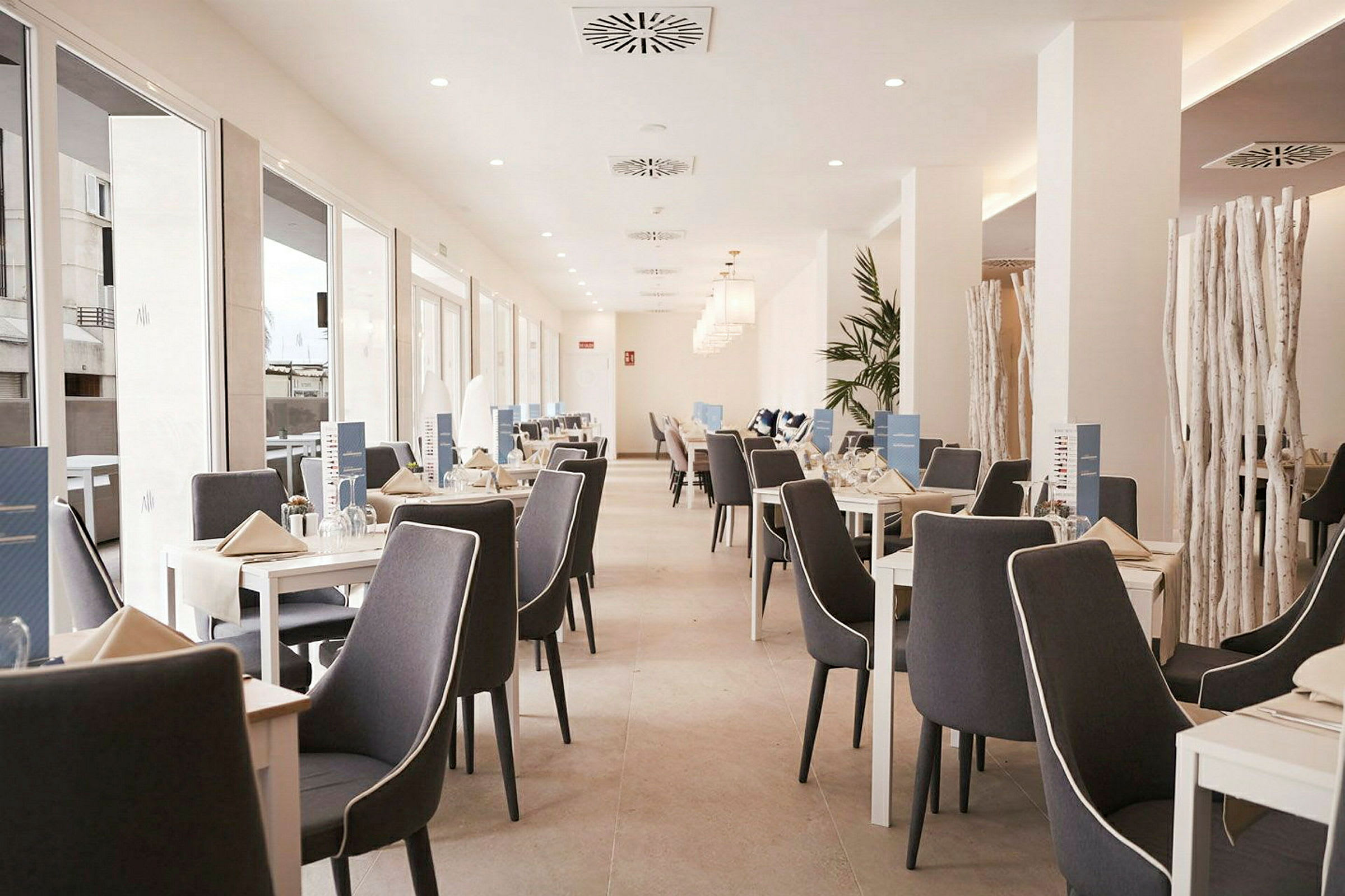 En lys restaurant med oppstilte bord og stoler. (AI-generert tekst)