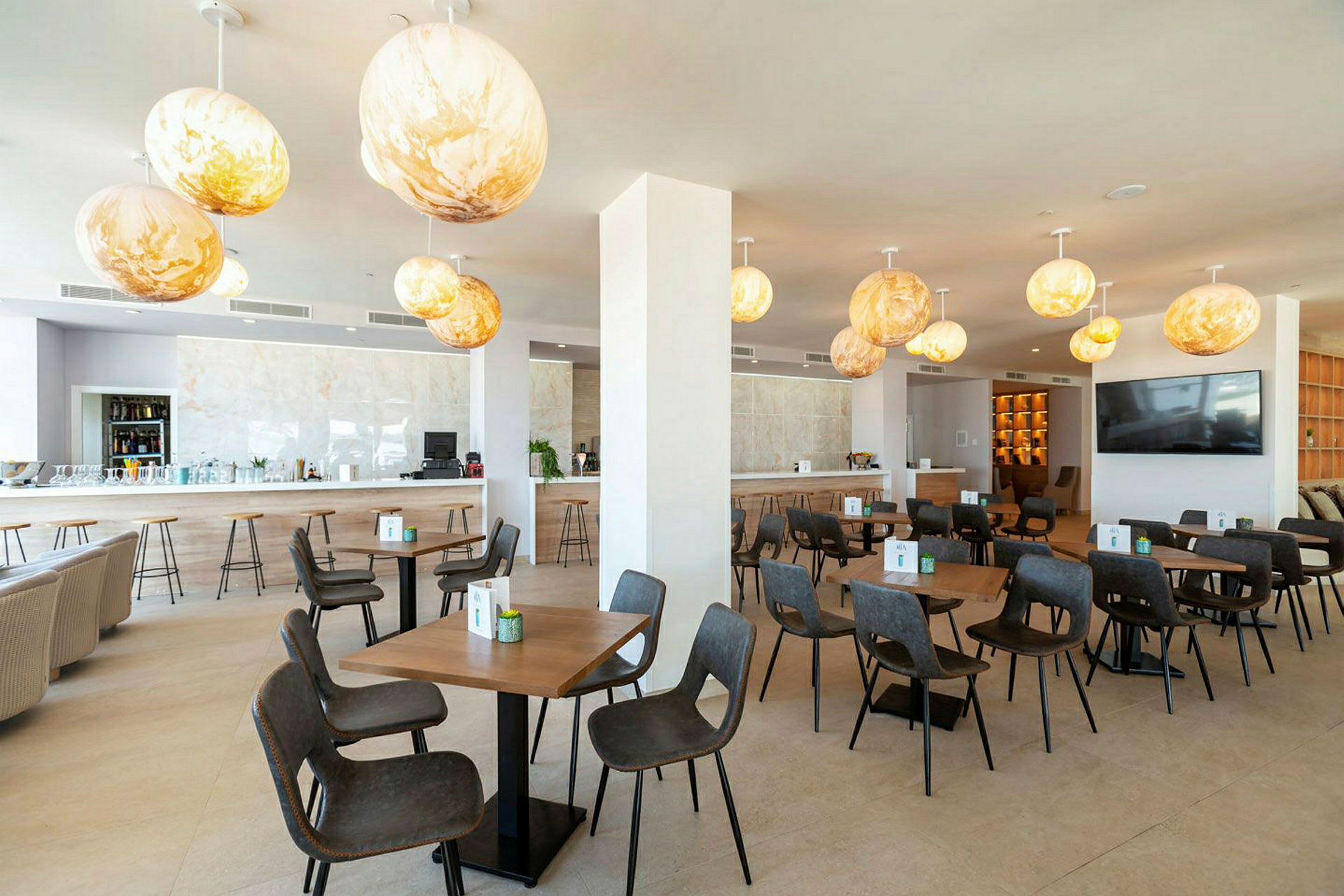 Bilde av en restaurant med moderne møbler og hengende dekorative lys. (AI-generert tekst)