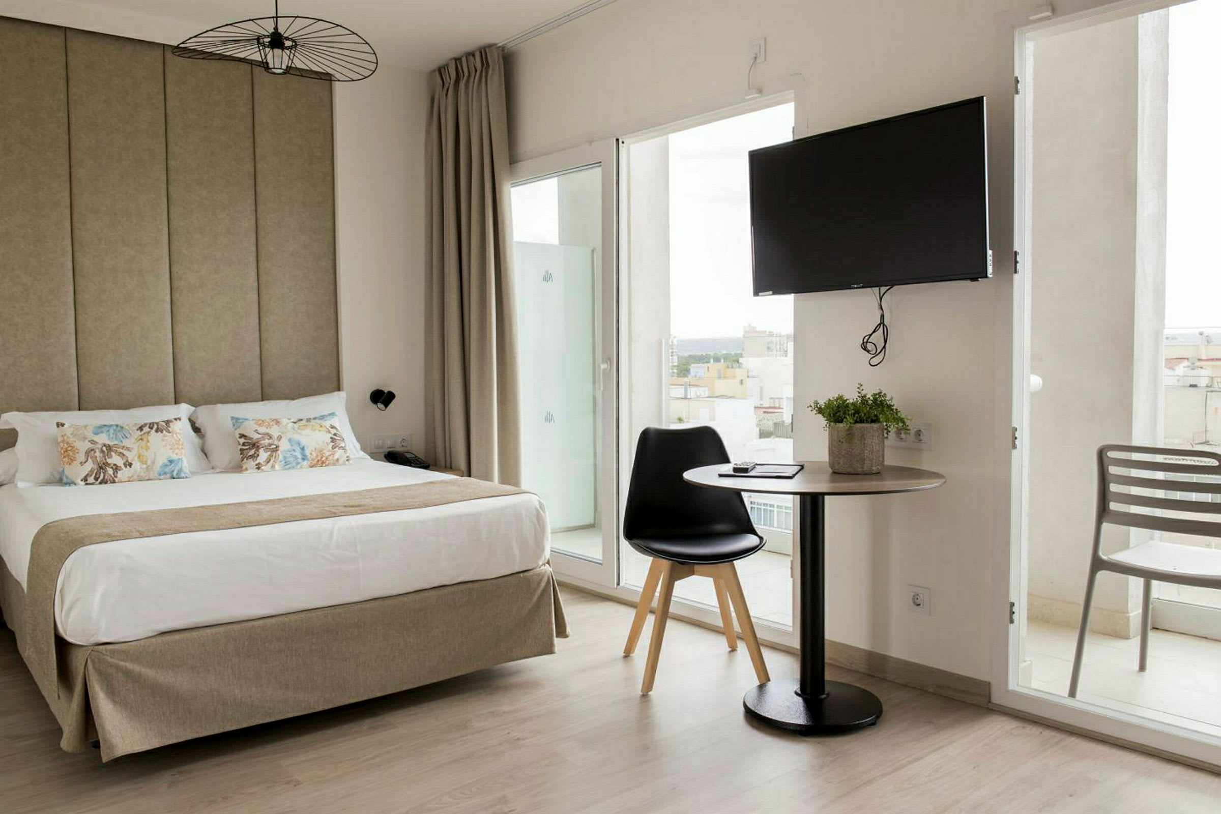 Hotellrom med en dobbeltseng, et bord med stol og en TV på veggen. (AI-generert tekst)
