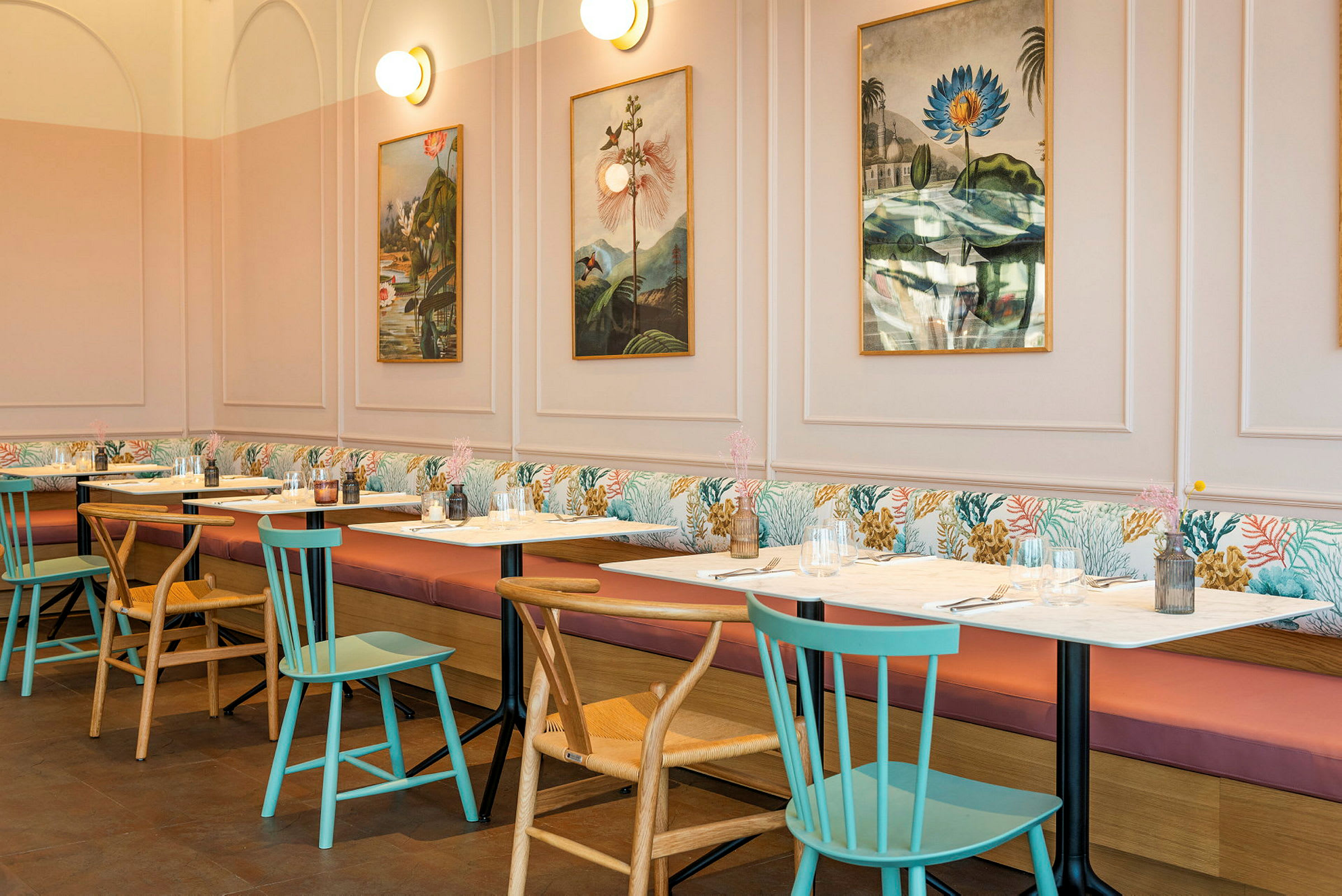 En restaurant med bord og stoler, bilder på veggen og myke sofaer langs veggen. (AI-generert tekst)