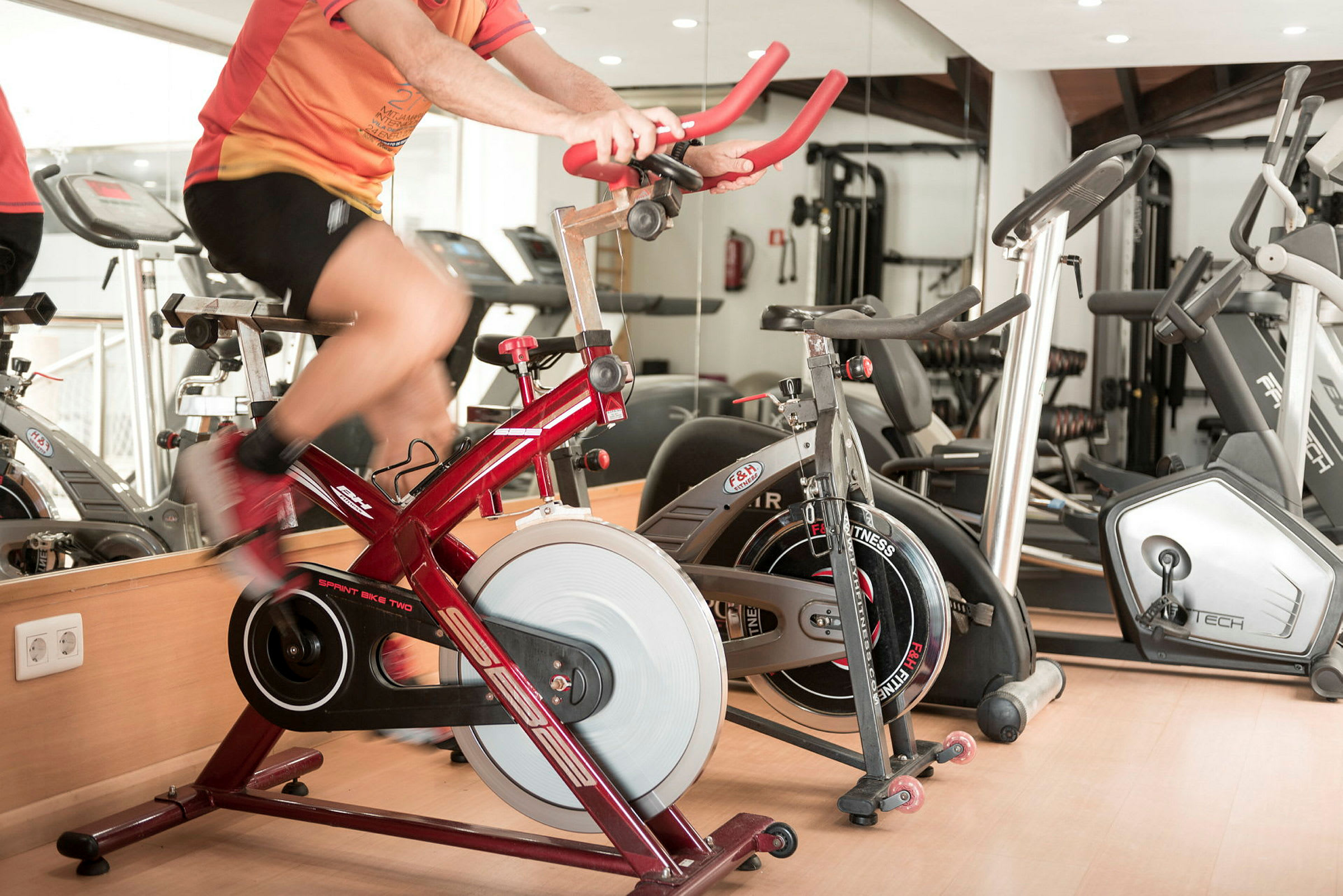 Person trener på en rød spinningsykkel i et treningsstudio. (AI-generert tekst)