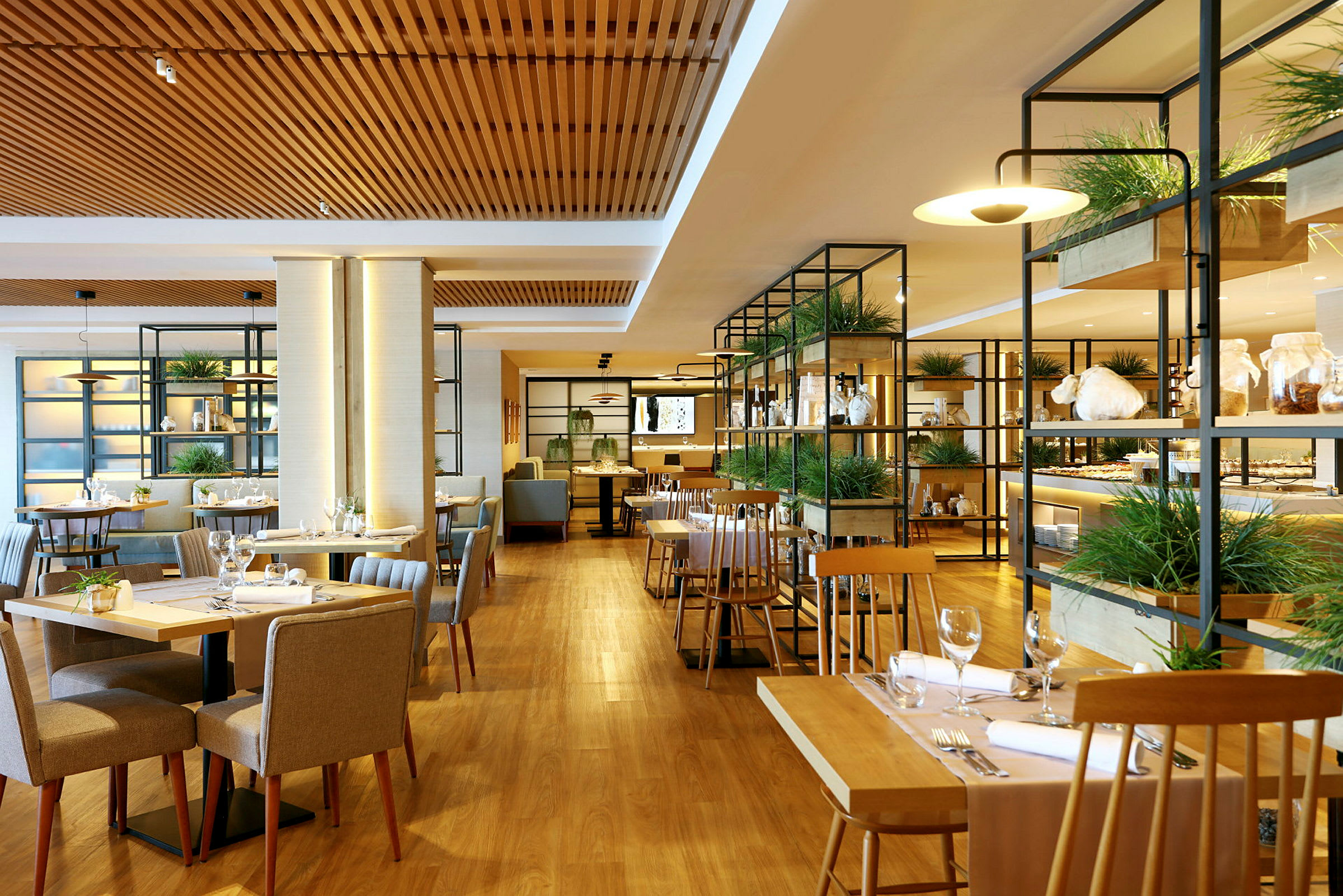 Bilde av en moderne restaurant med trebord og stoler, planter og glasshyller. (AI-generert tekst)