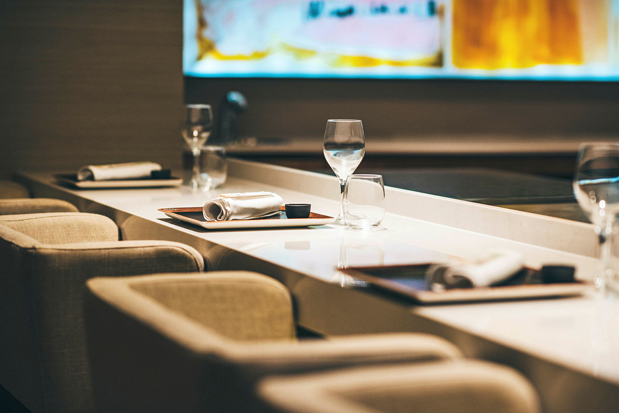 En rekke med bord satt opp med duk, inkludert glass, tallerkener og servietter, i en avslappet restaurant-setting. (AI-generert tekst)