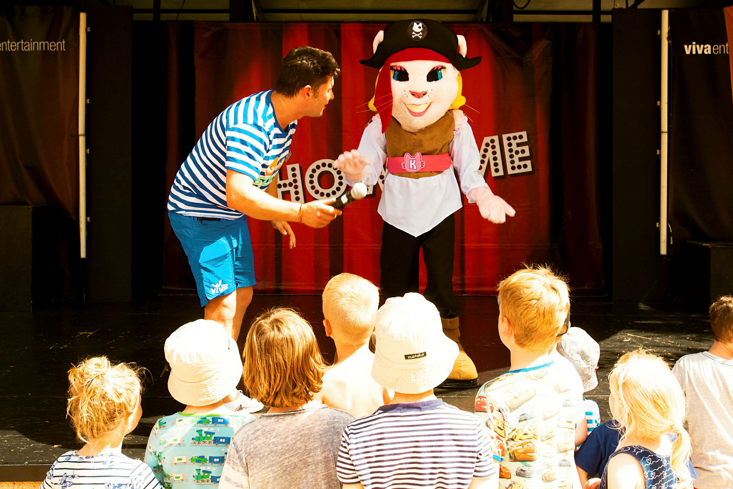 Sceneshow med personer i kostyme og publikum av barn. (AI-generert tekst)