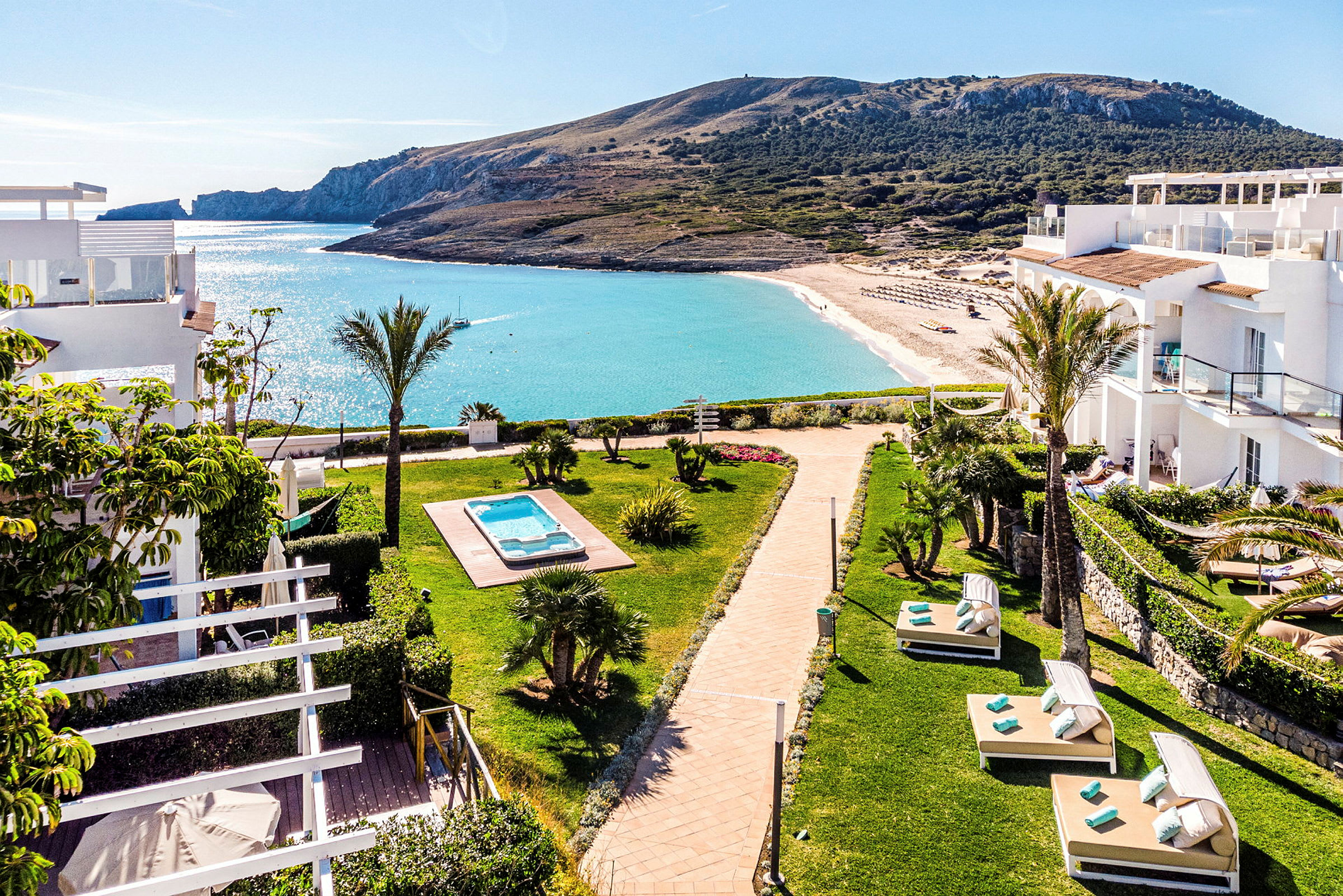 Utsikt over hotellområde med solsenger, basseng og strand i bakgrunnen. (AI-generert tekst)