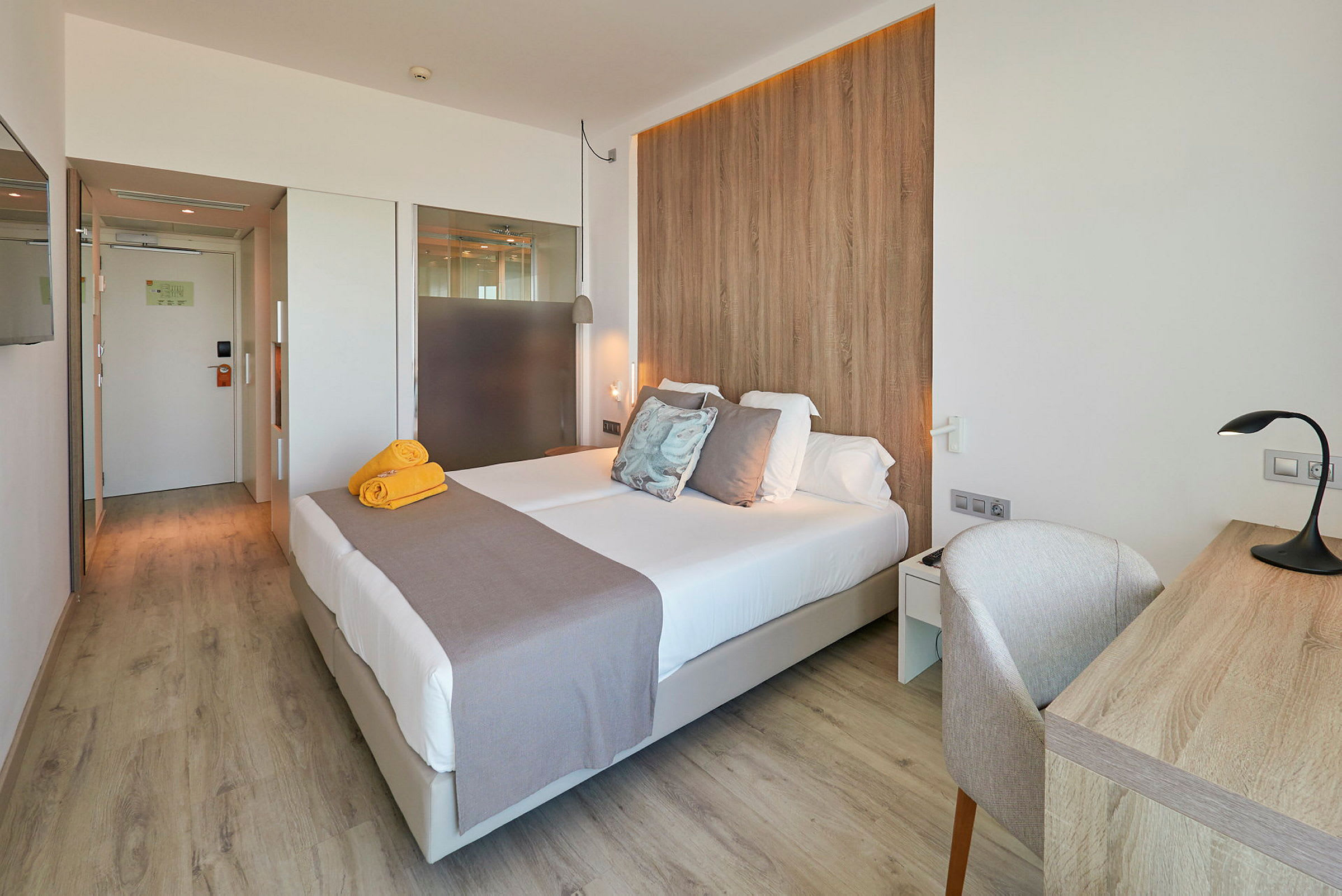 Et hotellrom med en dobbeltseng, skrivebord og tredetaljer. (AI-generert tekst)