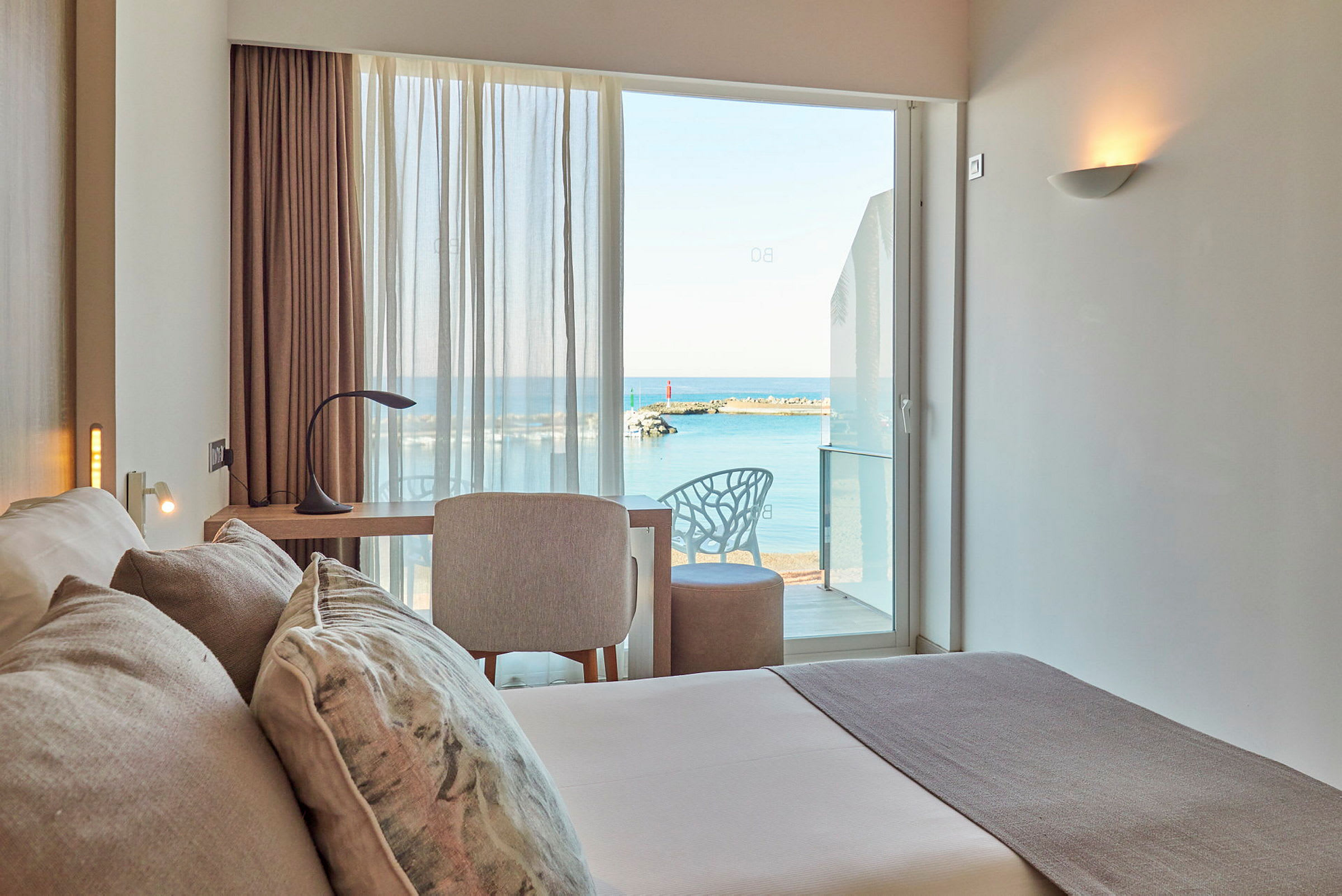 Et hotellrom med utsikt over havet gjennom vinduet. (AI-generert tekst)