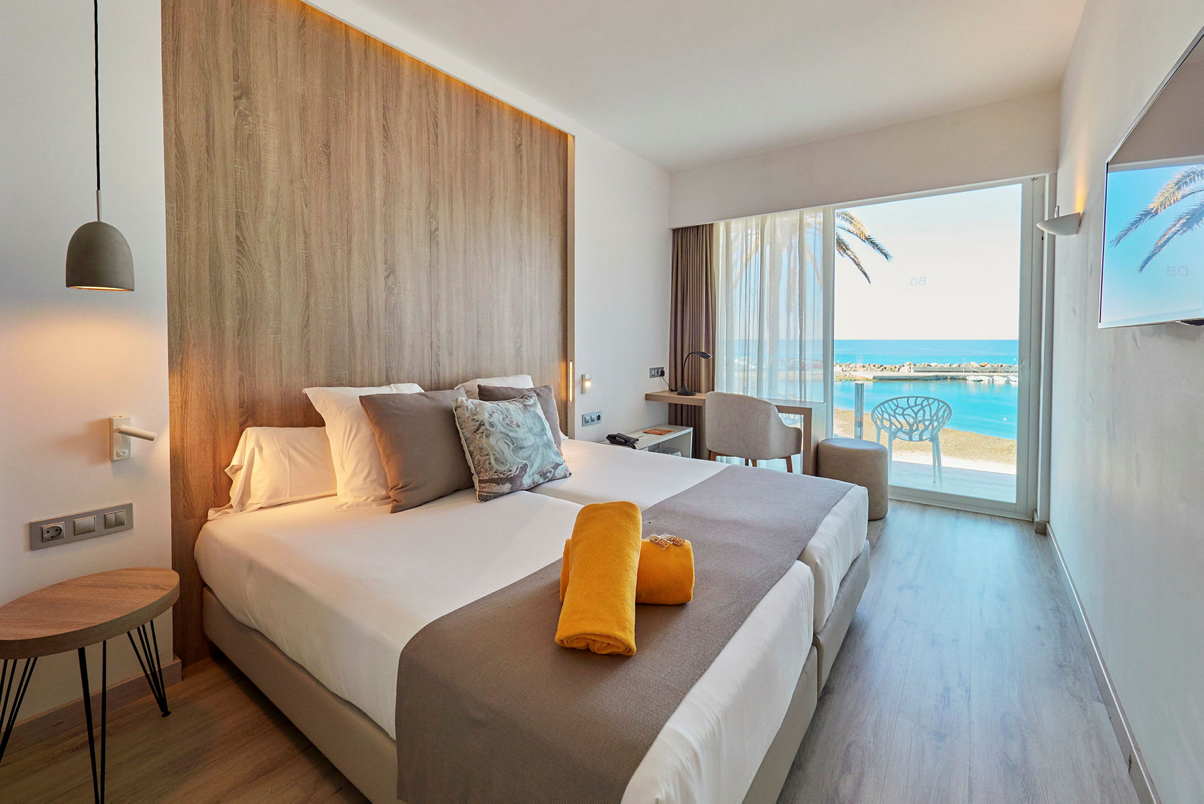 Moderne hotellrom med utsikt over havet gjennom en stor glassdør. (AI-generert tekst)