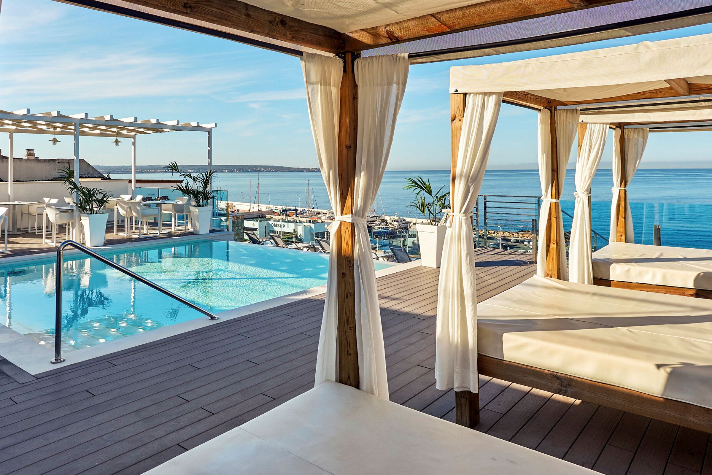 Terrasse med basseng, cabanas og utsikt over havet. (AI-generert tekst)