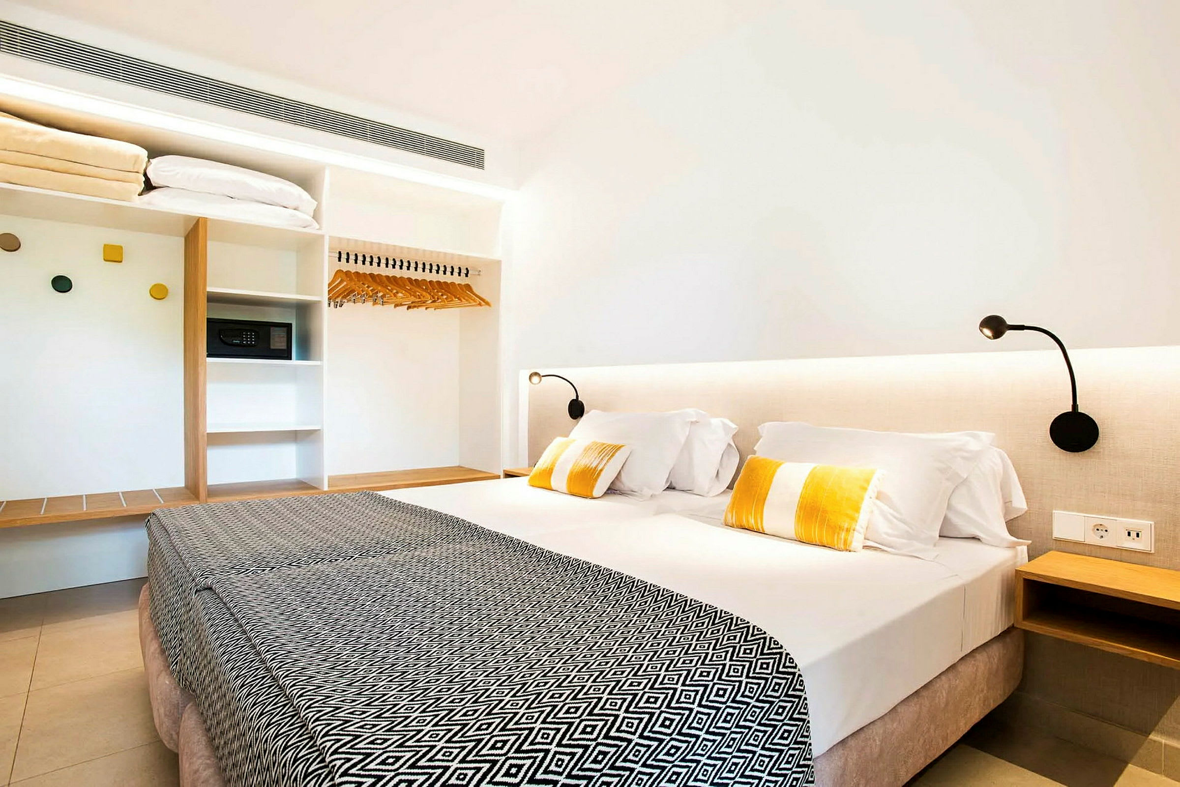 Hotellrom med en dobbeltseng, leselamper og en garderobe. (AI-generert tekst)