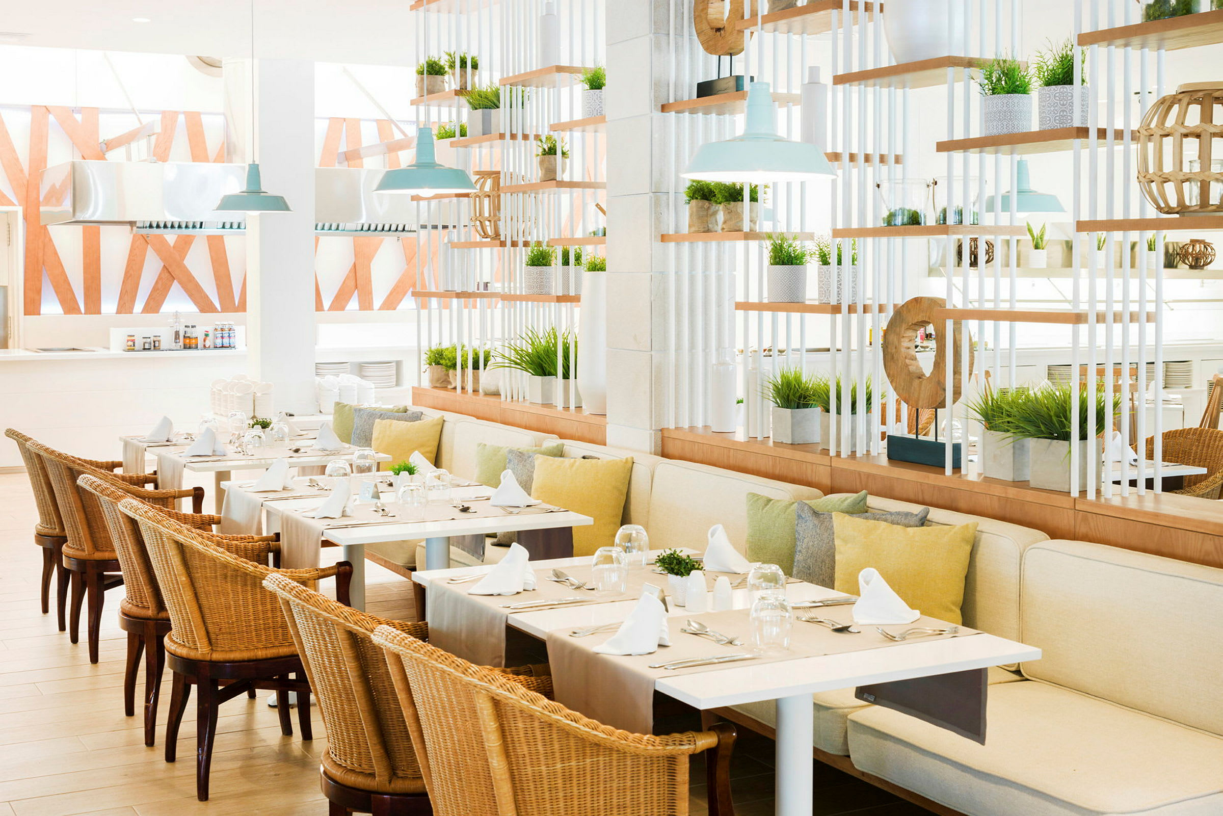 Bilde av en lys og luftig restaurant med bord dekket med hvite servietter og omkringliggende planter. (AI-generert tekst)