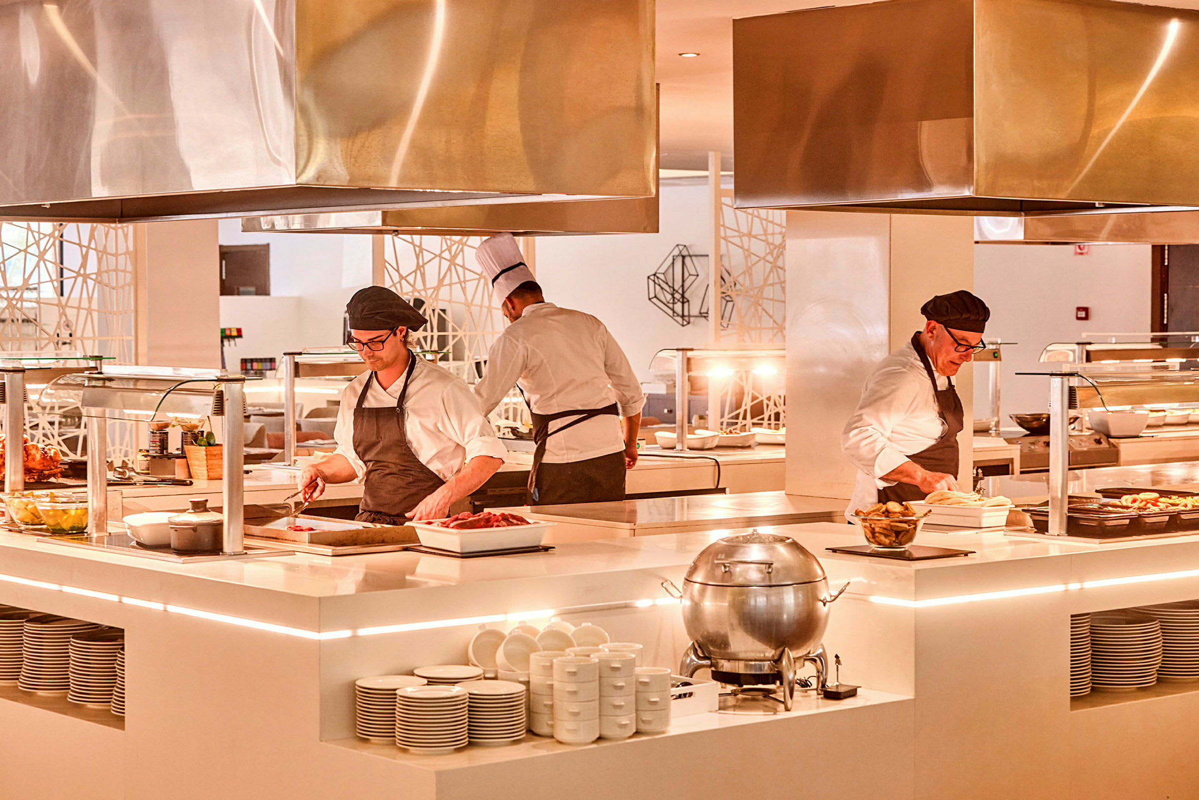Kokker arbeider ved en moderne buffetstasjon i et opplyst kjøkkenområde. (AI-generert tekst)