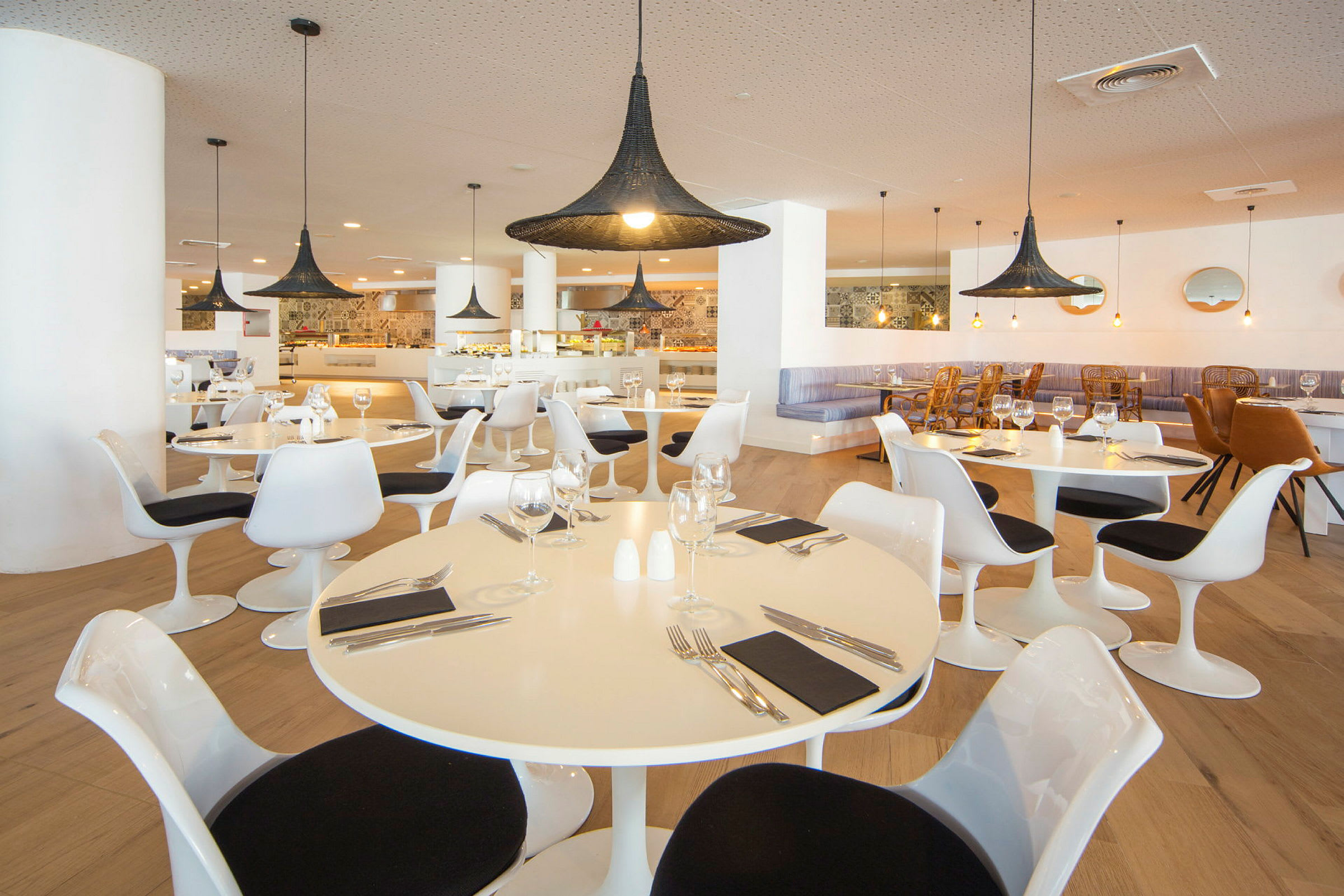 Bilde av en restaurant med moderne hvite bord og stoler, og store svarte lamper. (AI-generert tekst)