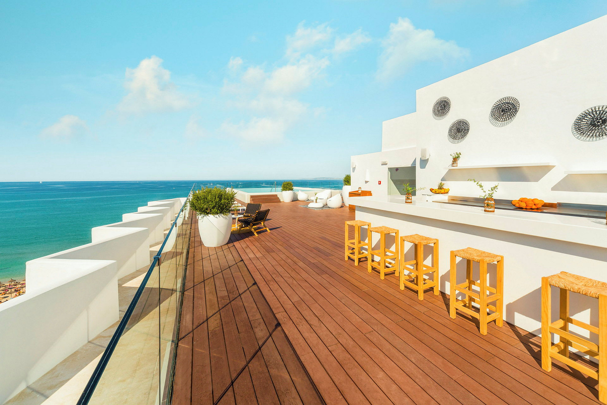 Takterrasse med bar, sittemøbler og utsikt over havet. (AI-generert tekst)