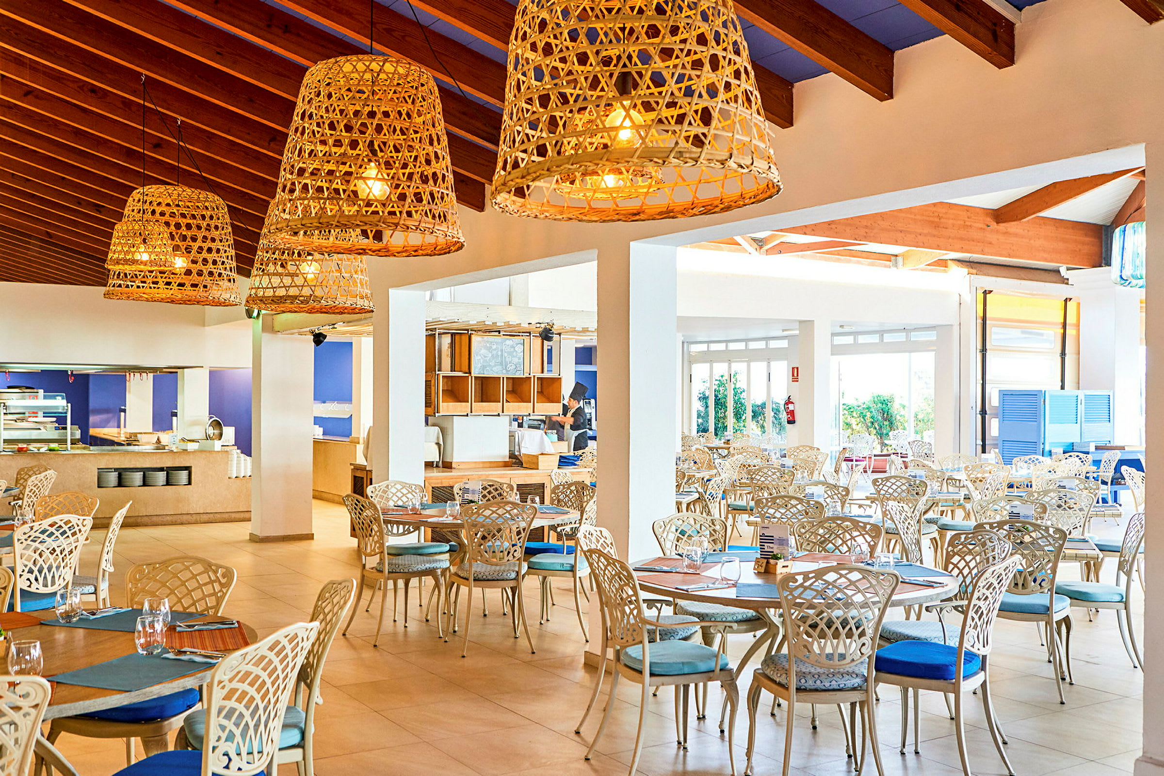 Lys og luftig restaurant med elegant møblement og store kurvlamper. (AI-generert tekst)
