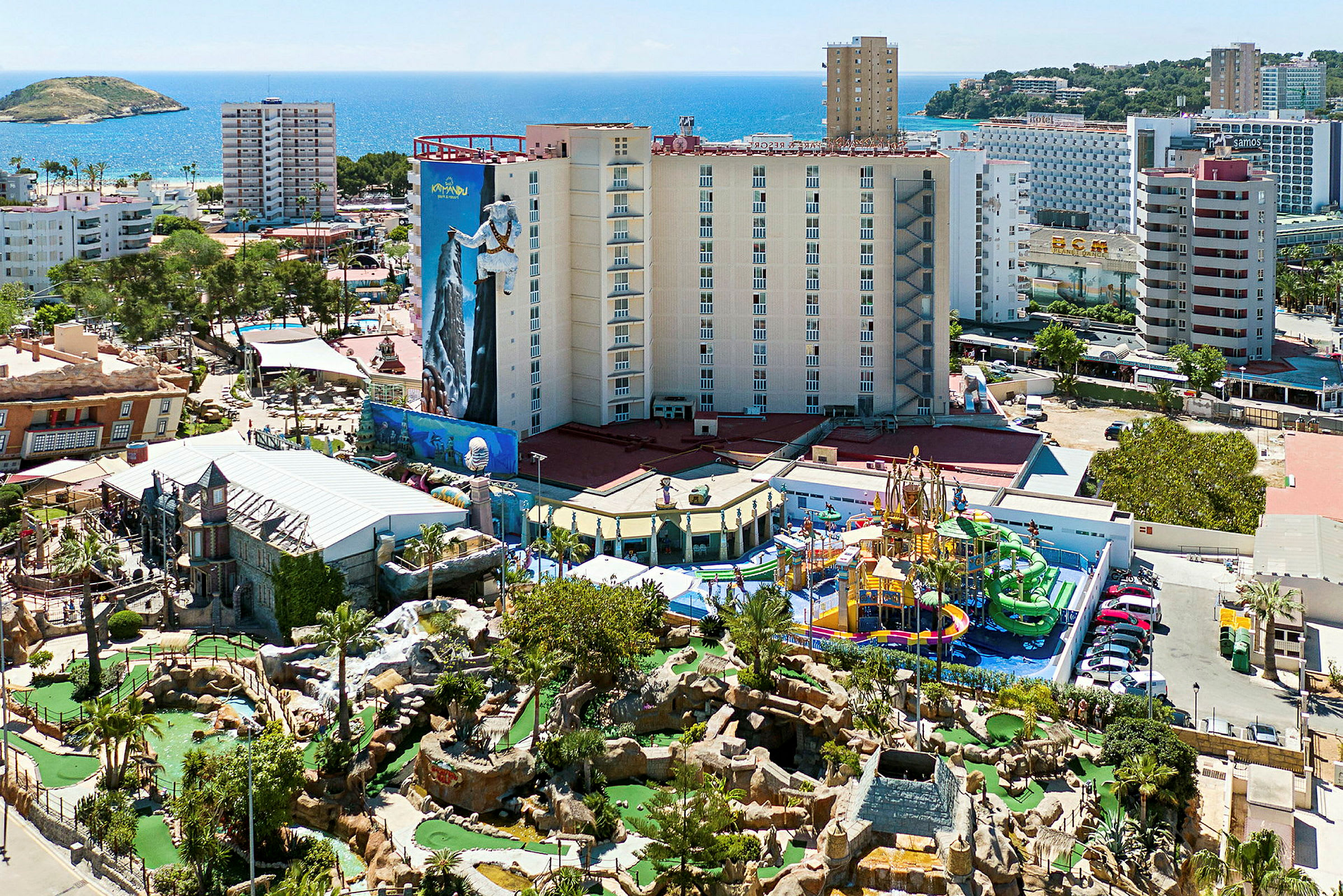 Utsikt over et hotellområde med fornøyelsespark og havet i bakgrunnen. (AI-generert tekst)