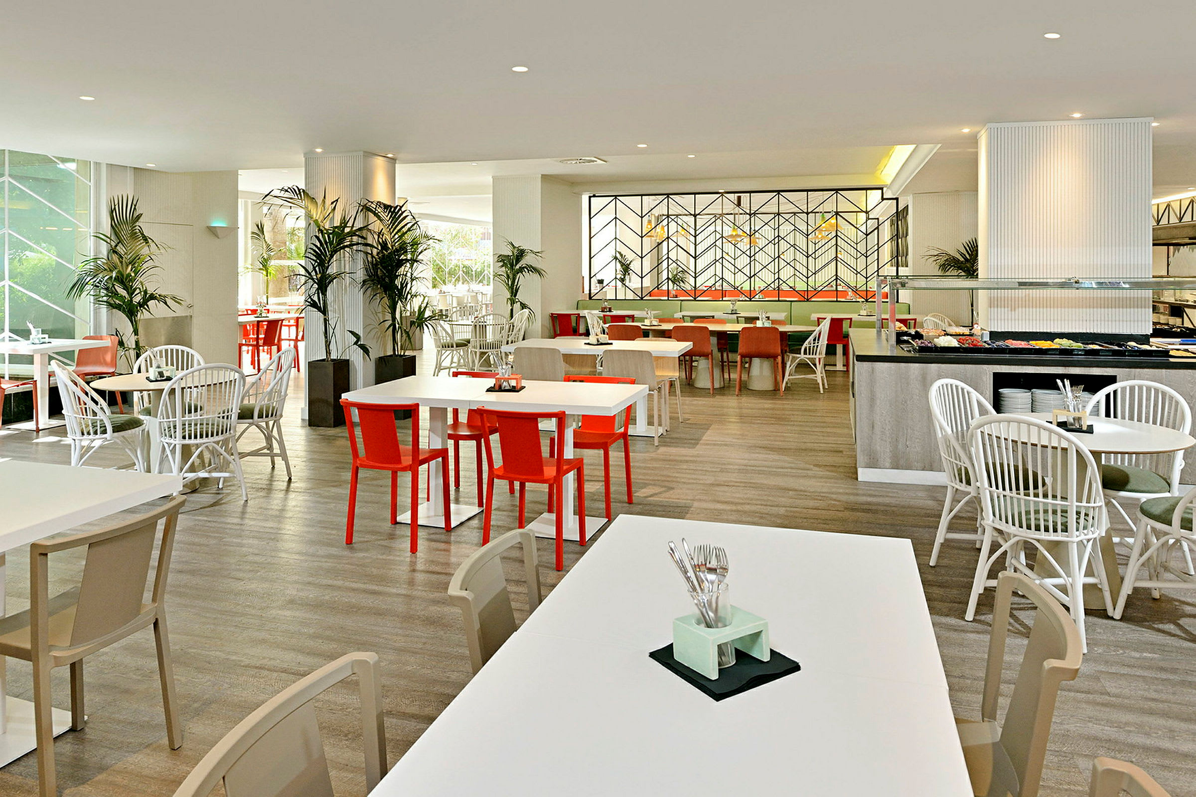 En lys og moderne restaurant med hvite bord og fargerike stoler. (AI-generert tekst)