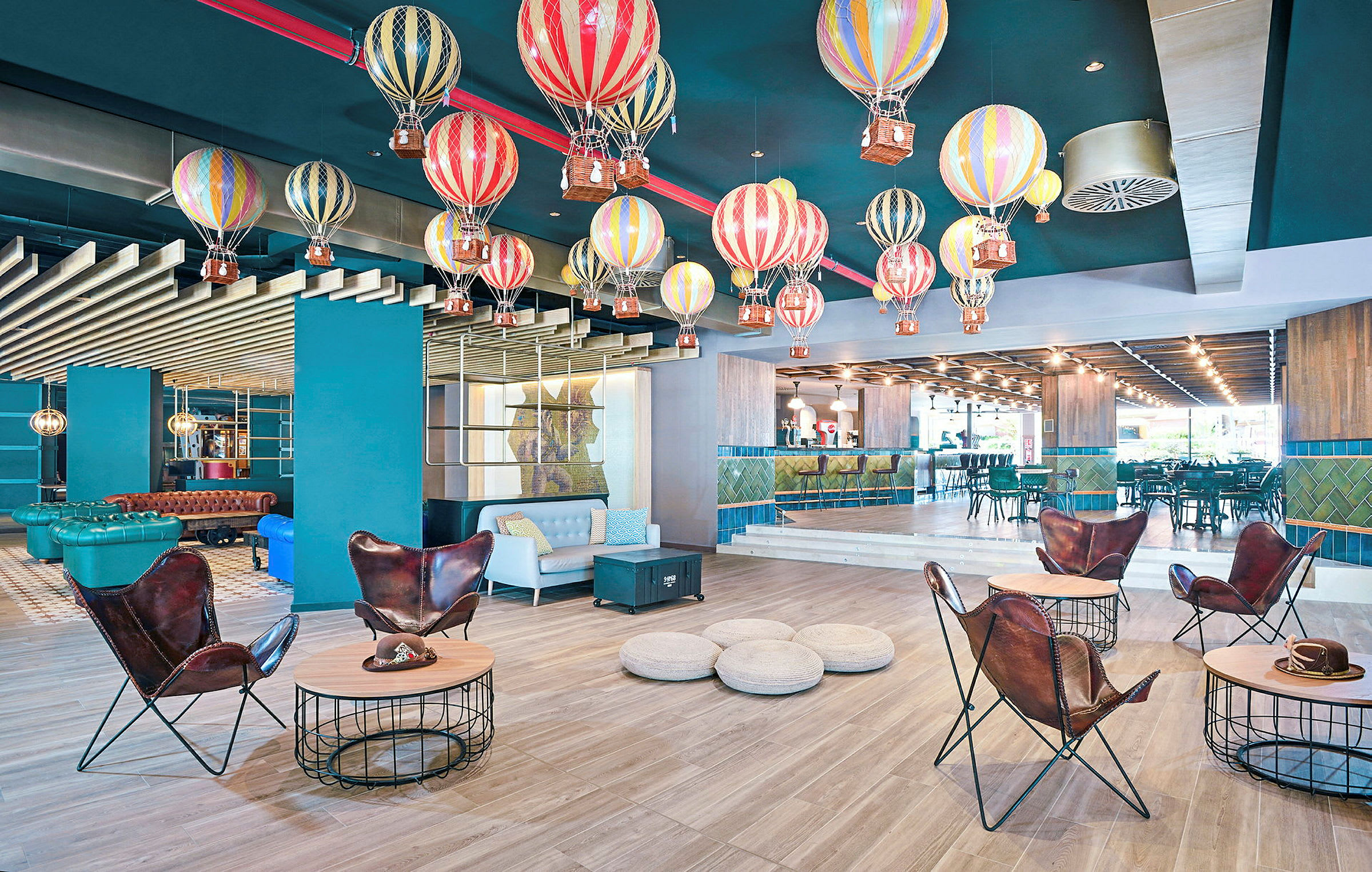 Et rom med fargerike luftballonger hengende fra taket som dekor, moderne møbler og en bar i bakgrunnen. (AI-generert tekst)