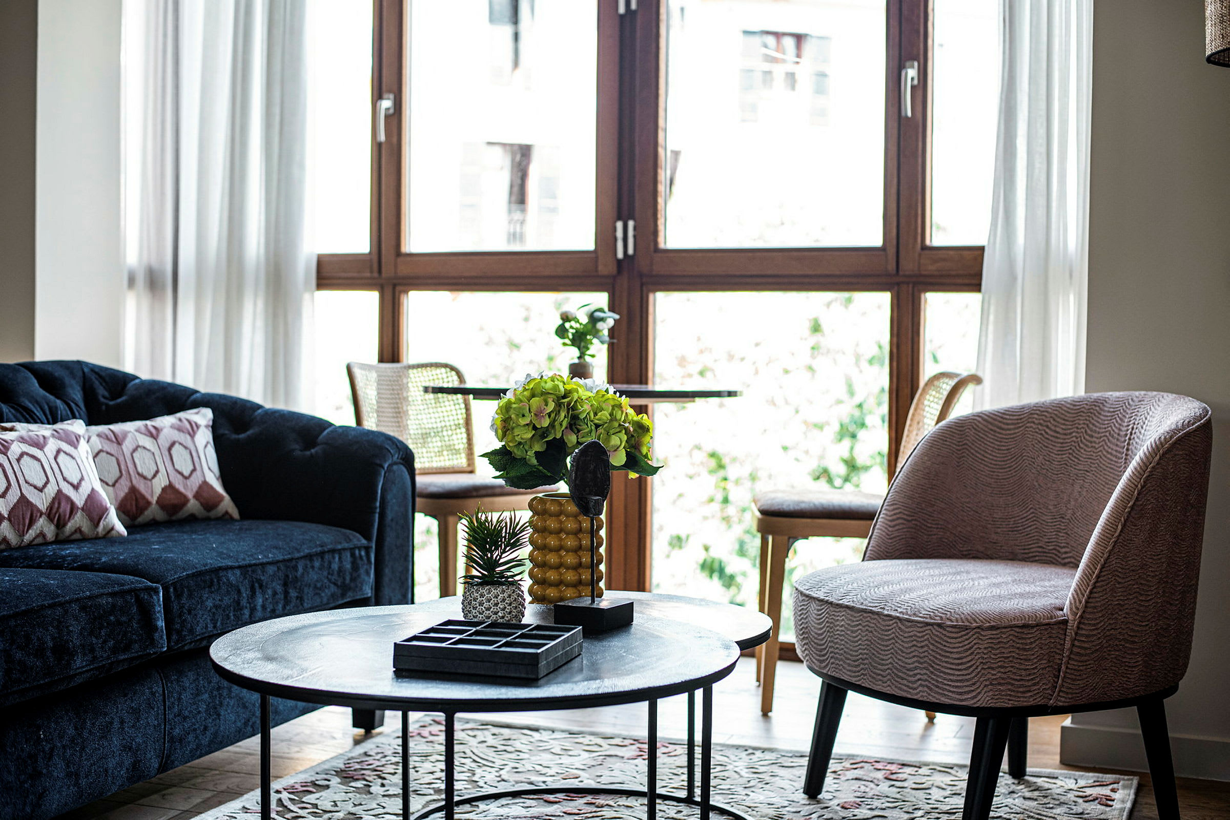 Stue med blå sofa, rund bordlampe og store vinduer. (AI-generert tekst)