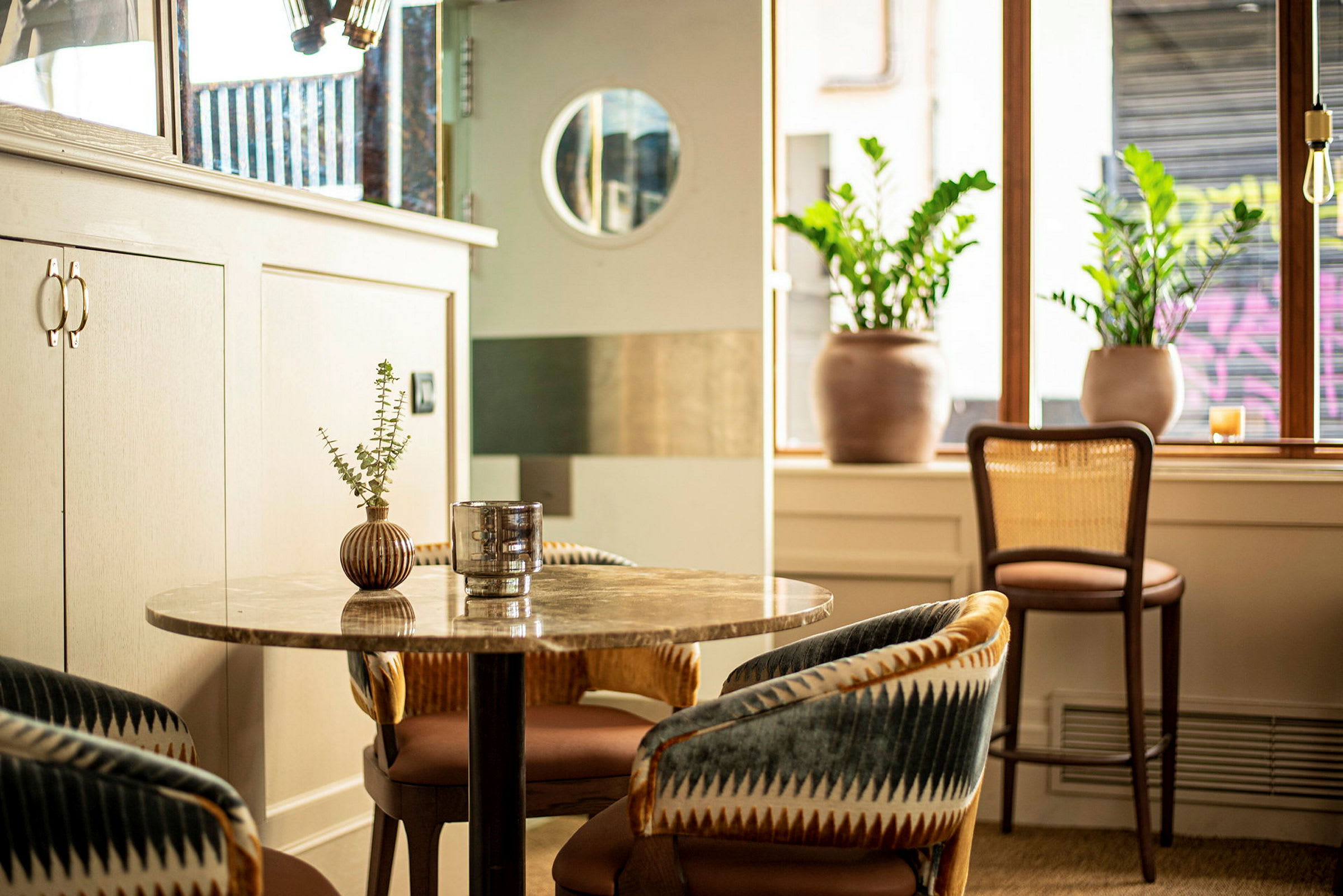 En moderne kafé med loungestoler, et bord og planter. (AI-generert tekst)