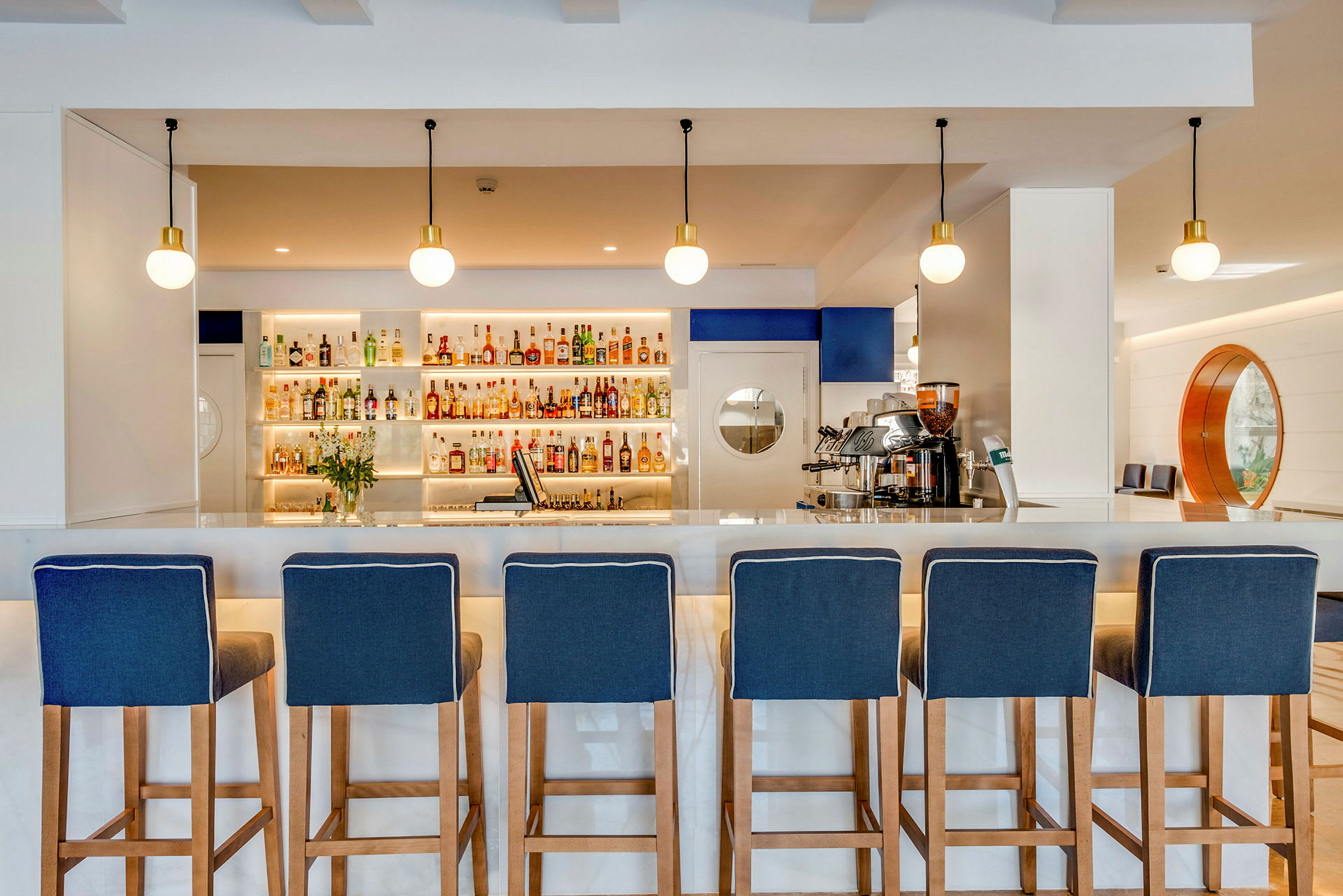 En bar med blå barkrakker foran en hylle med forskjellige drikker. (AI-generert tekst)