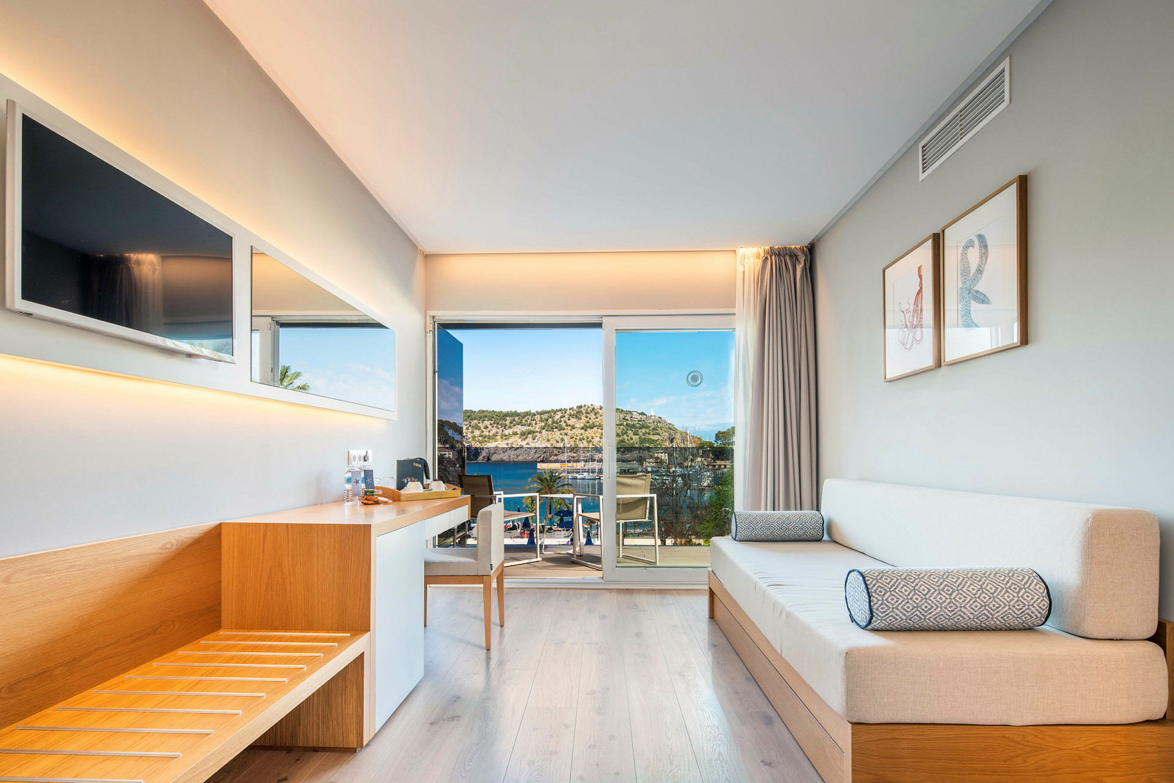 Et moderne hotellrom med treinteriør, sofa og utsikt over havet gjennom en glassdør. (AI-generert tekst)