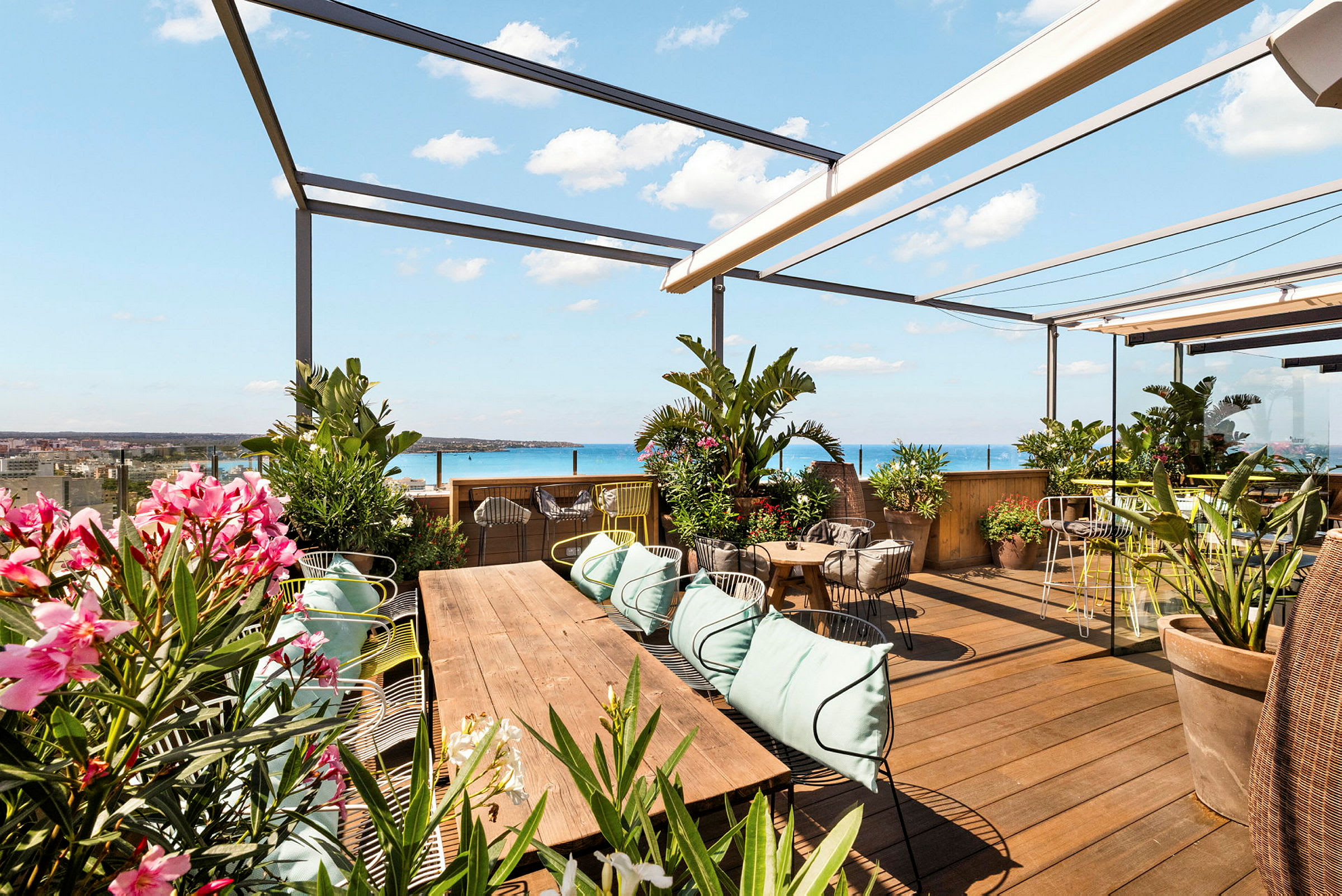 En takterrasse med sitteplasser, grønne planter og utsikt mot havet. (AI-generert tekst)