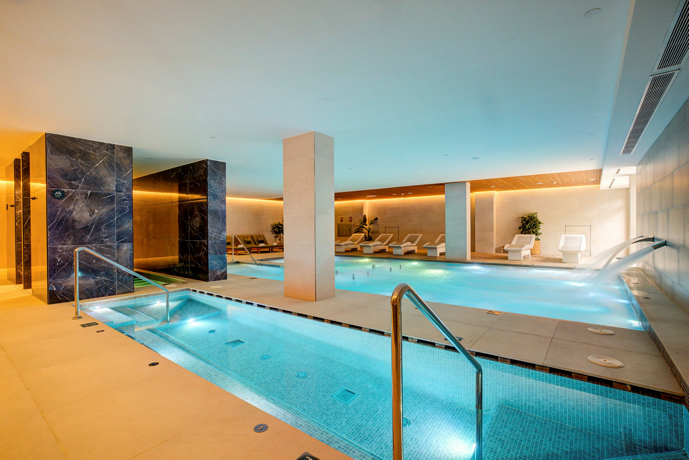 Et moderne spa med et innendørsbasseng og avslappingsområder. (AI-generert tekst)