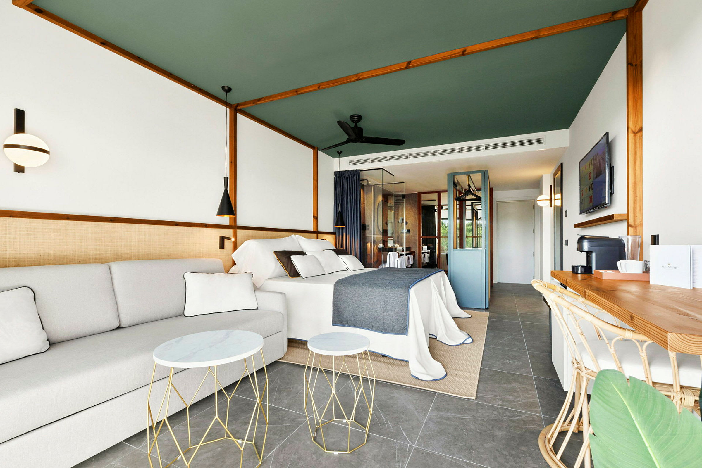 Moderne innredet hotellrom med seng, sofa og arbeidsområde. (AI-generert tekst)