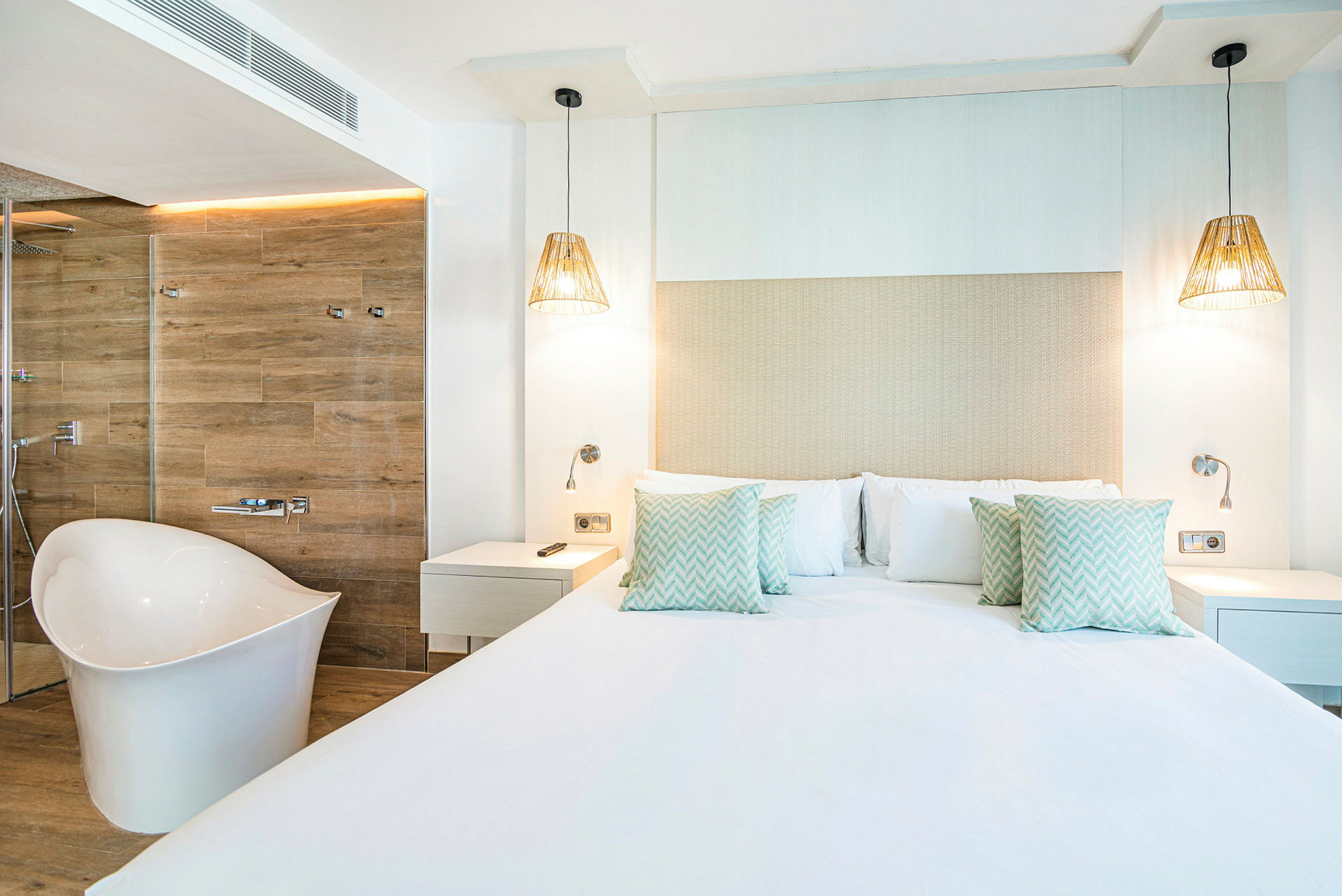 Et moderne hotellrom med en stor seng, hvite vegger og et frittstående badekar. (AI-generert tekst)