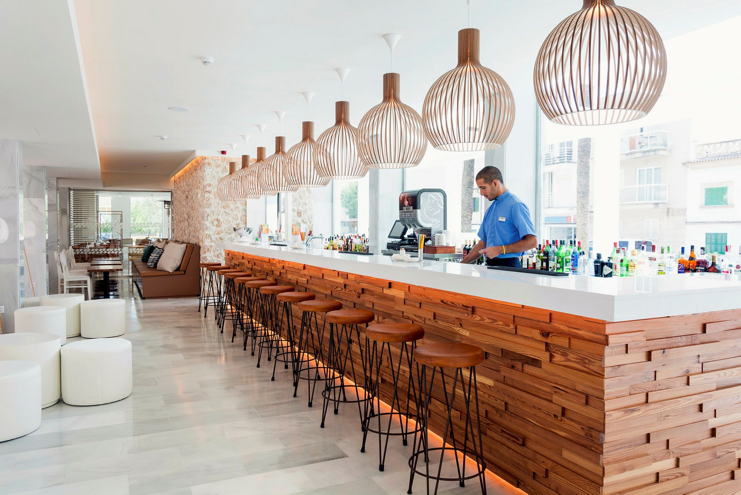 En moderne bar med tre detaljer og store lamper hengende over bardisken. (AI-generert tekst)