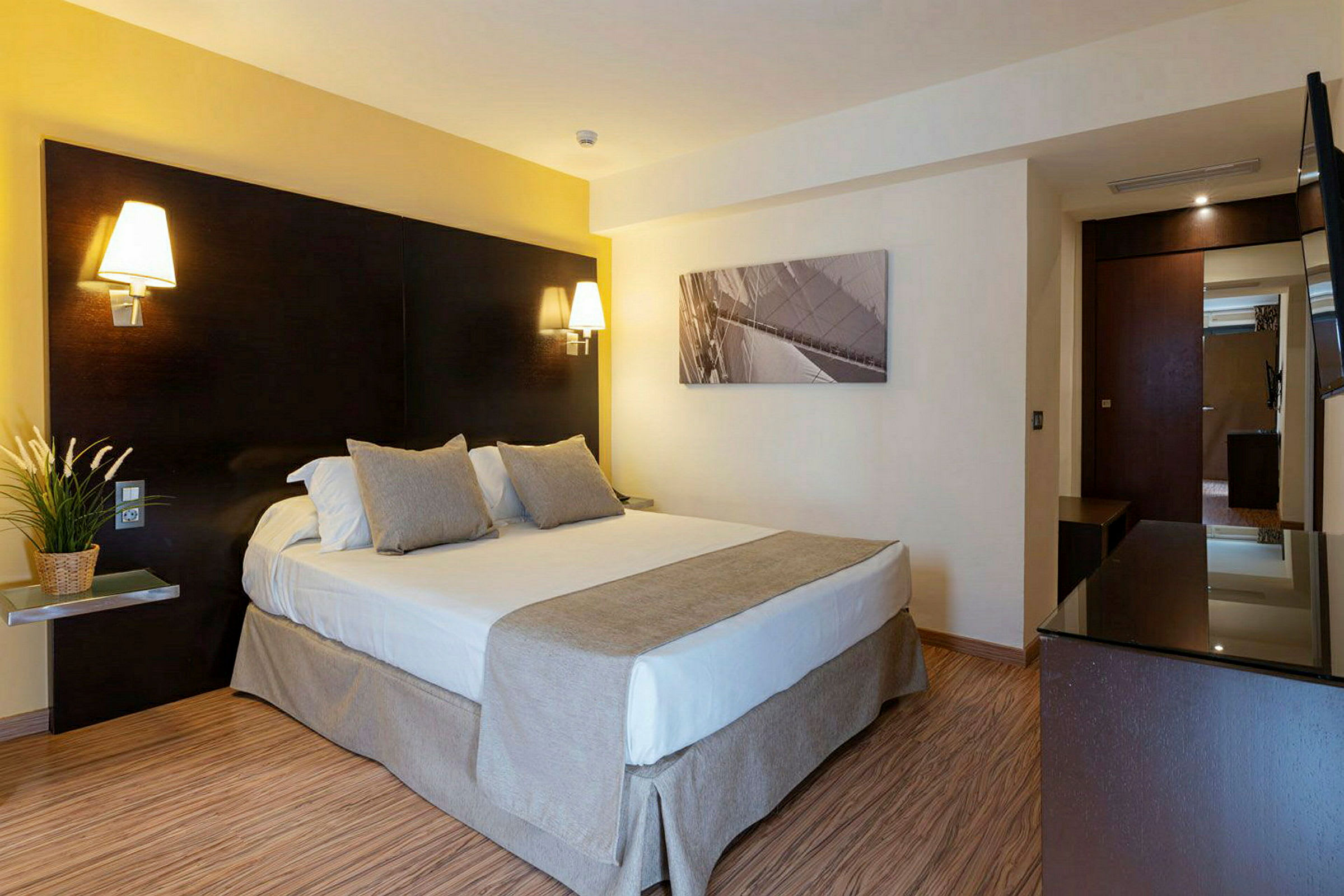 Et hotellrom med en dobbeltseng, nattlamper og et bilde på veggen. (AI-generert tekst)