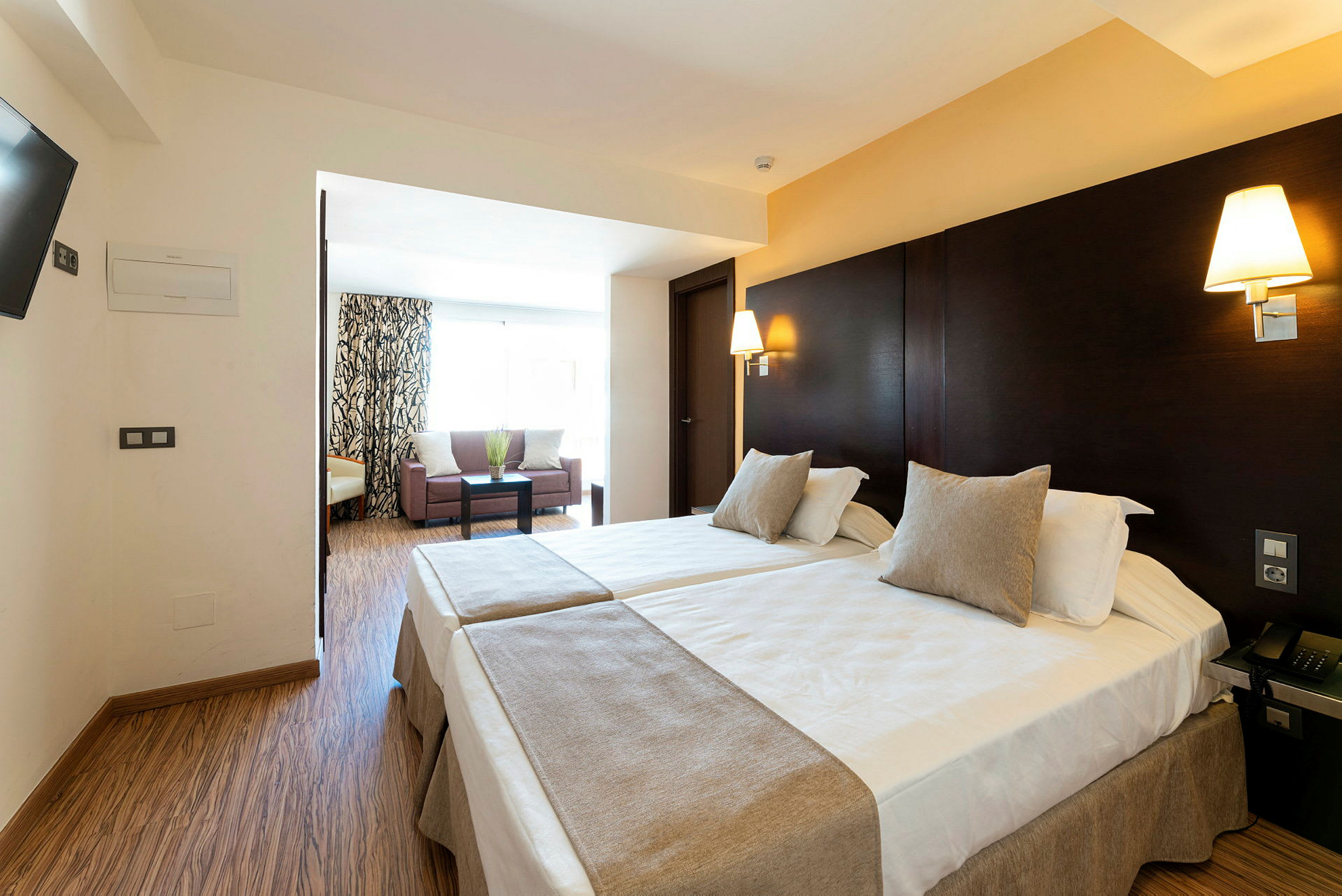 Hotellrom med to enkeltsenger og en sitteavdeling. (AI-generert tekst)