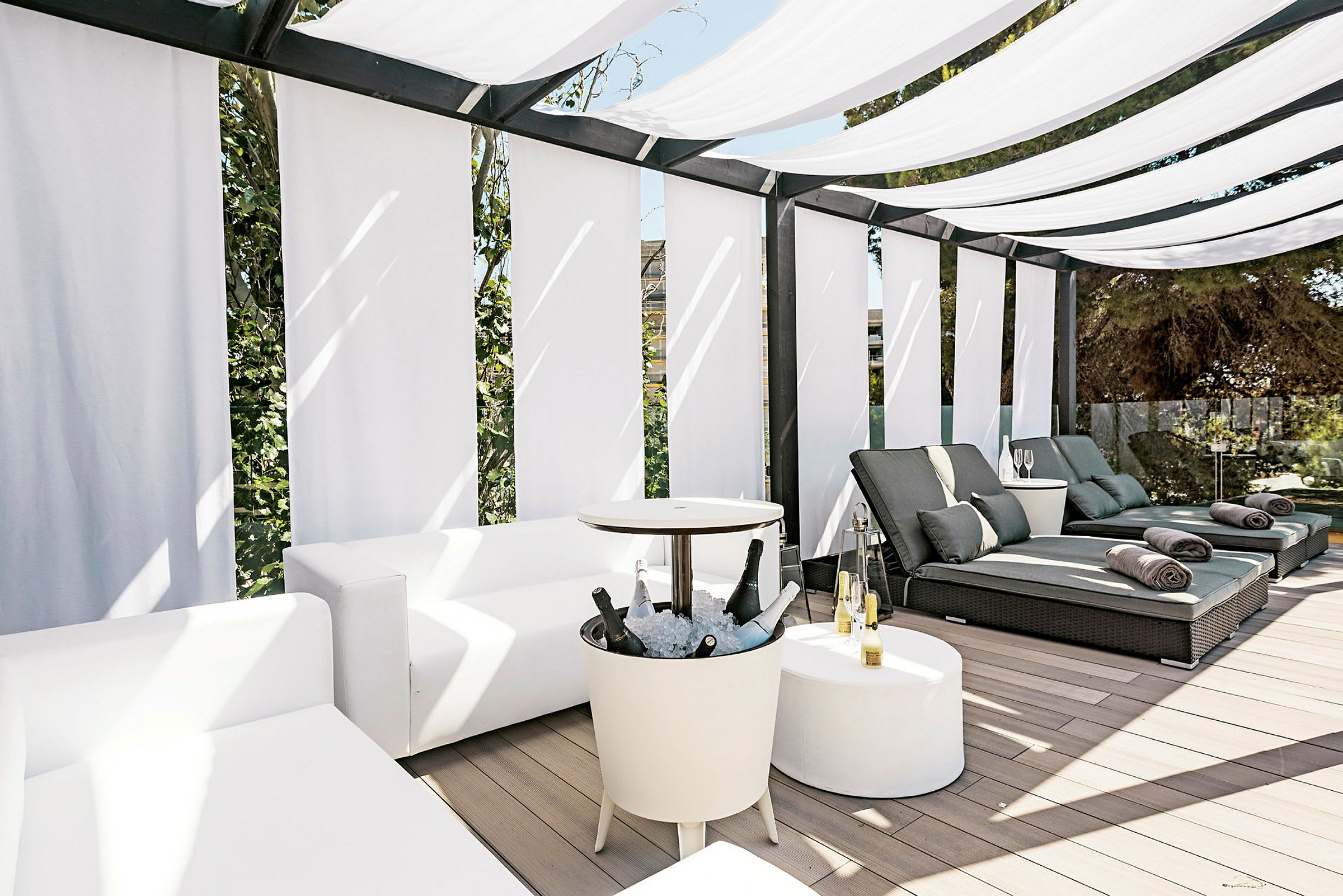 Utendørs lounge med hvite sofaer, solsenger og solskjerming. (AI-generert tekst)